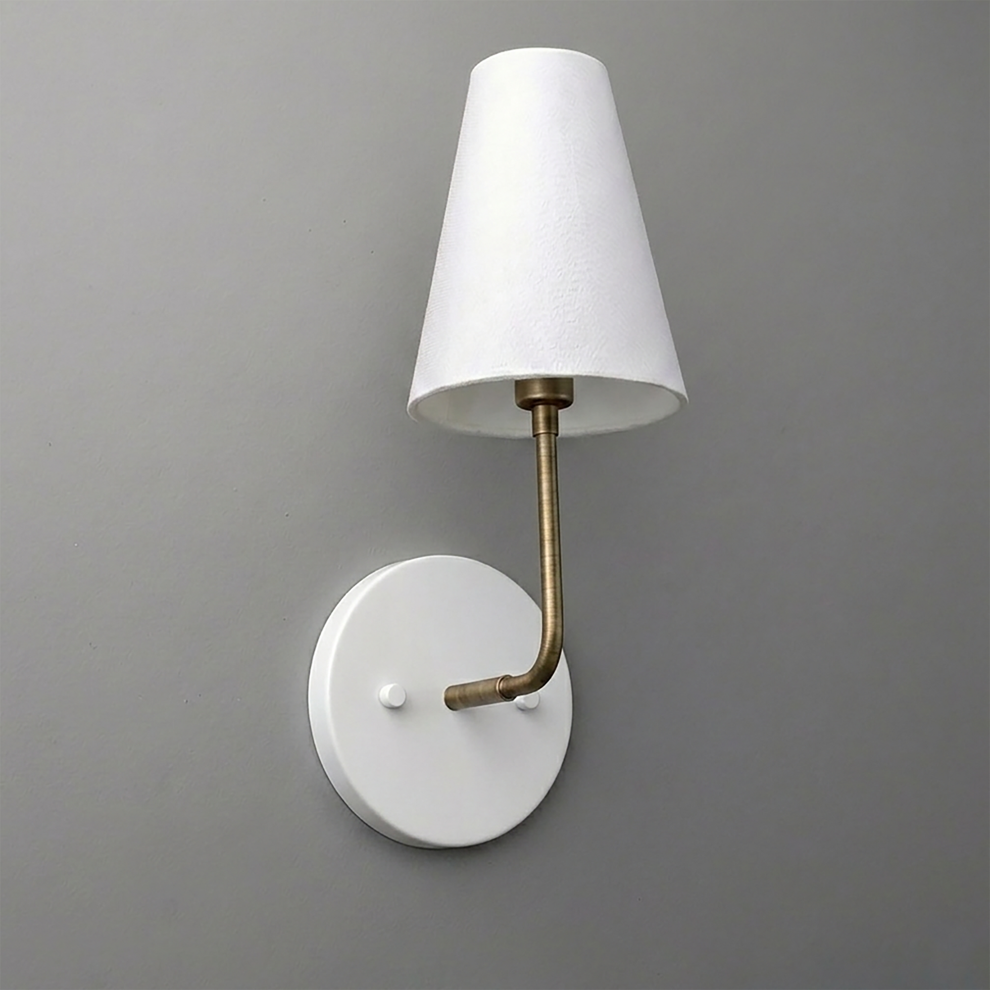 White round wall sconce with brass curved arm and white tapered fabric shade. - SCONCE MODEL NO. 3928