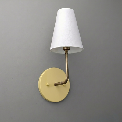 Wall sconce with a round beige base, brass arm, and white tapered fabric lampshade. - SCONCE MODEL NO. 3928