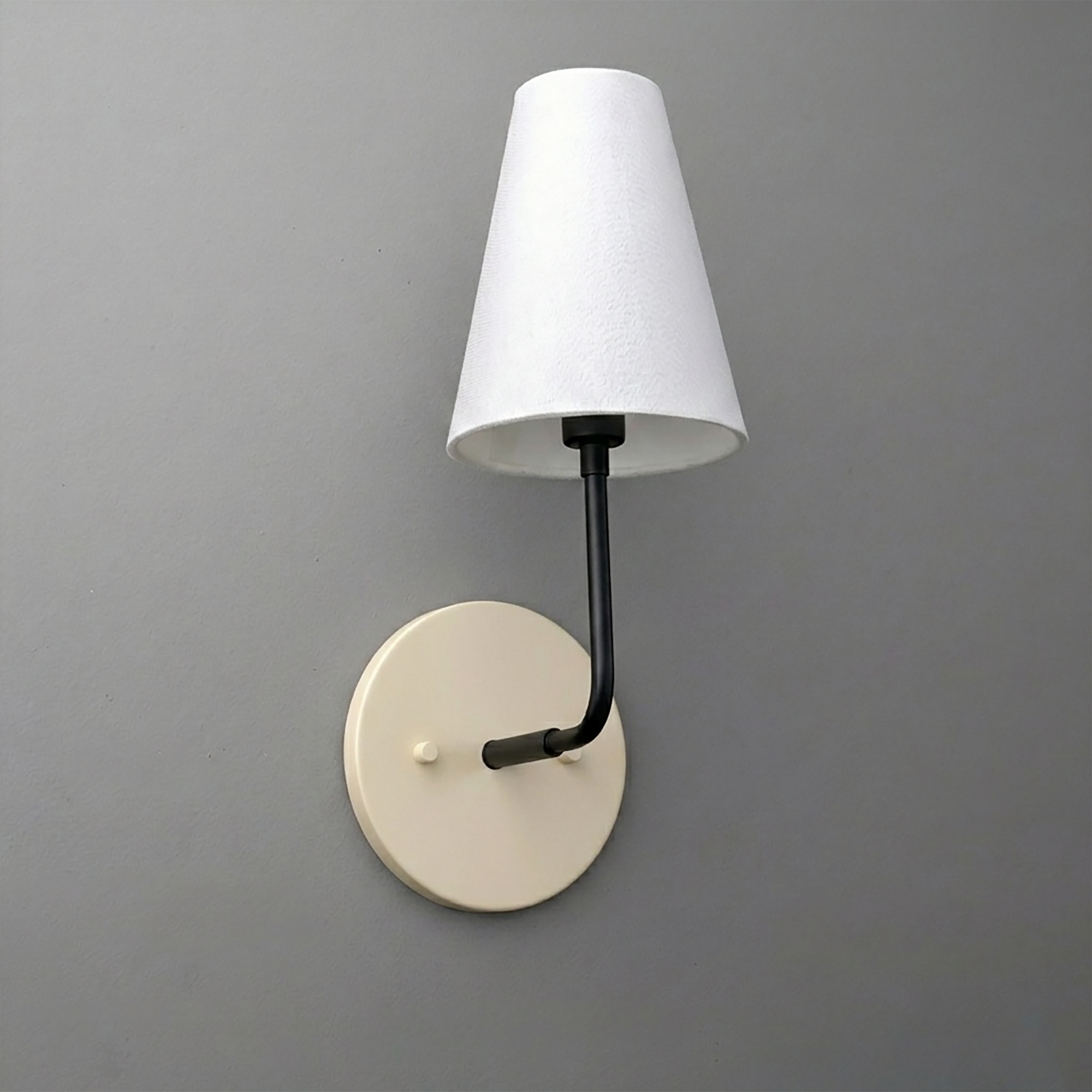 Wall sconce with ivory round base, black metal arm, and white tapered fabric shade. - SCONCE MODEL NO. 3928