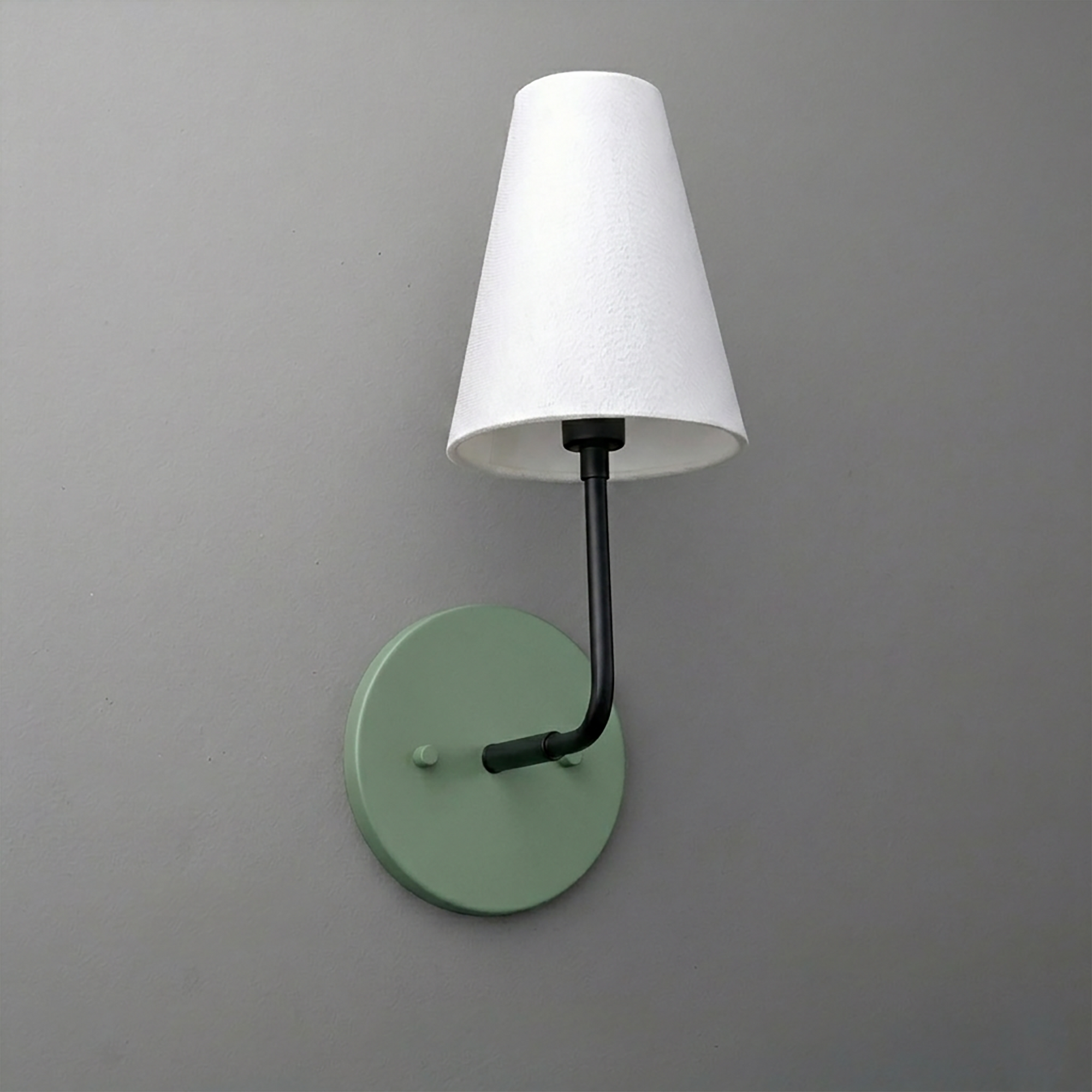 Wall-mounted sconce with matte green round base and black arm holding a white tapered fabric shade. - SCONCE MODEL NO. 3928