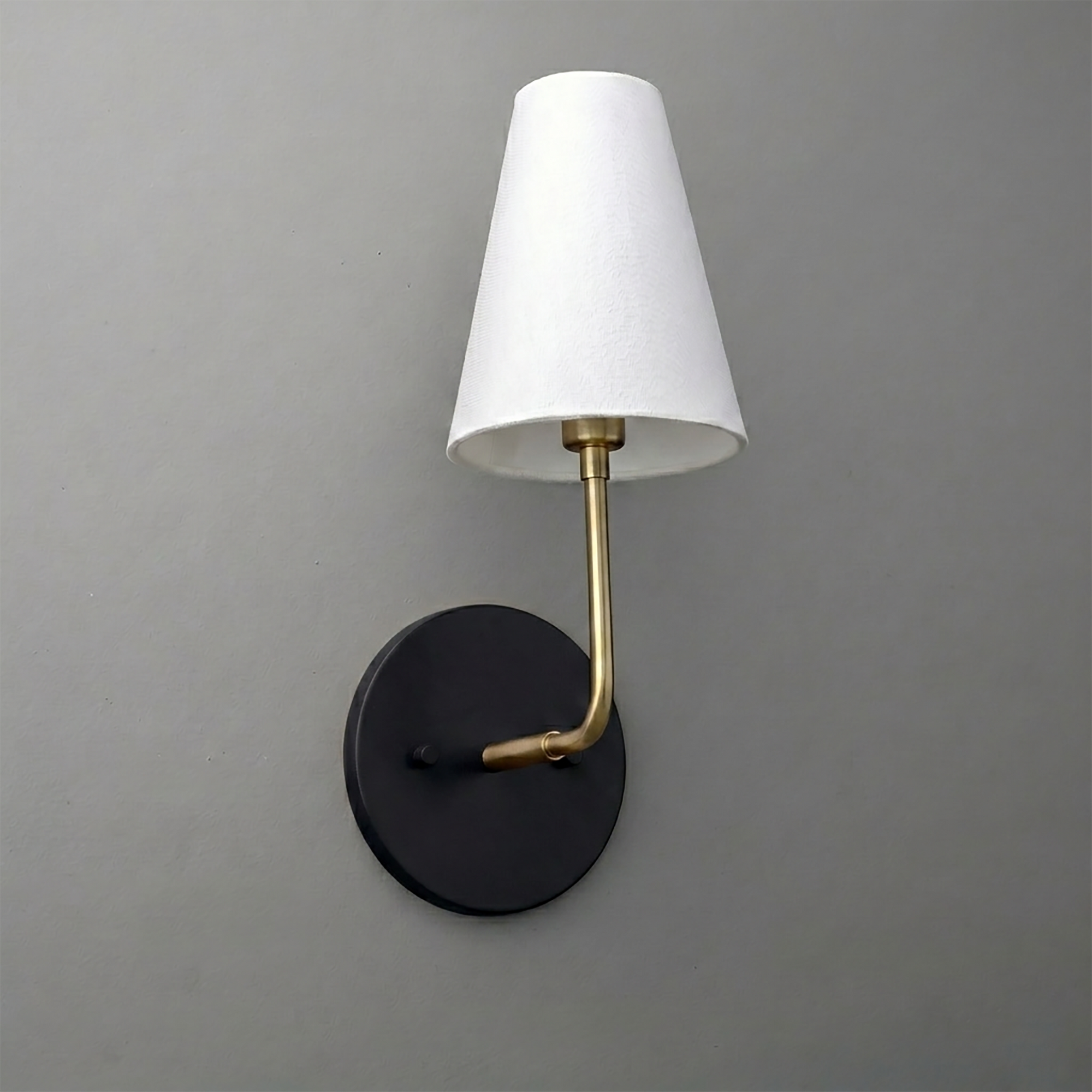 Wall sconce with black round base, brass arm, and white tapered fabric lampshade. - SCONCE MODEL NO. 3928