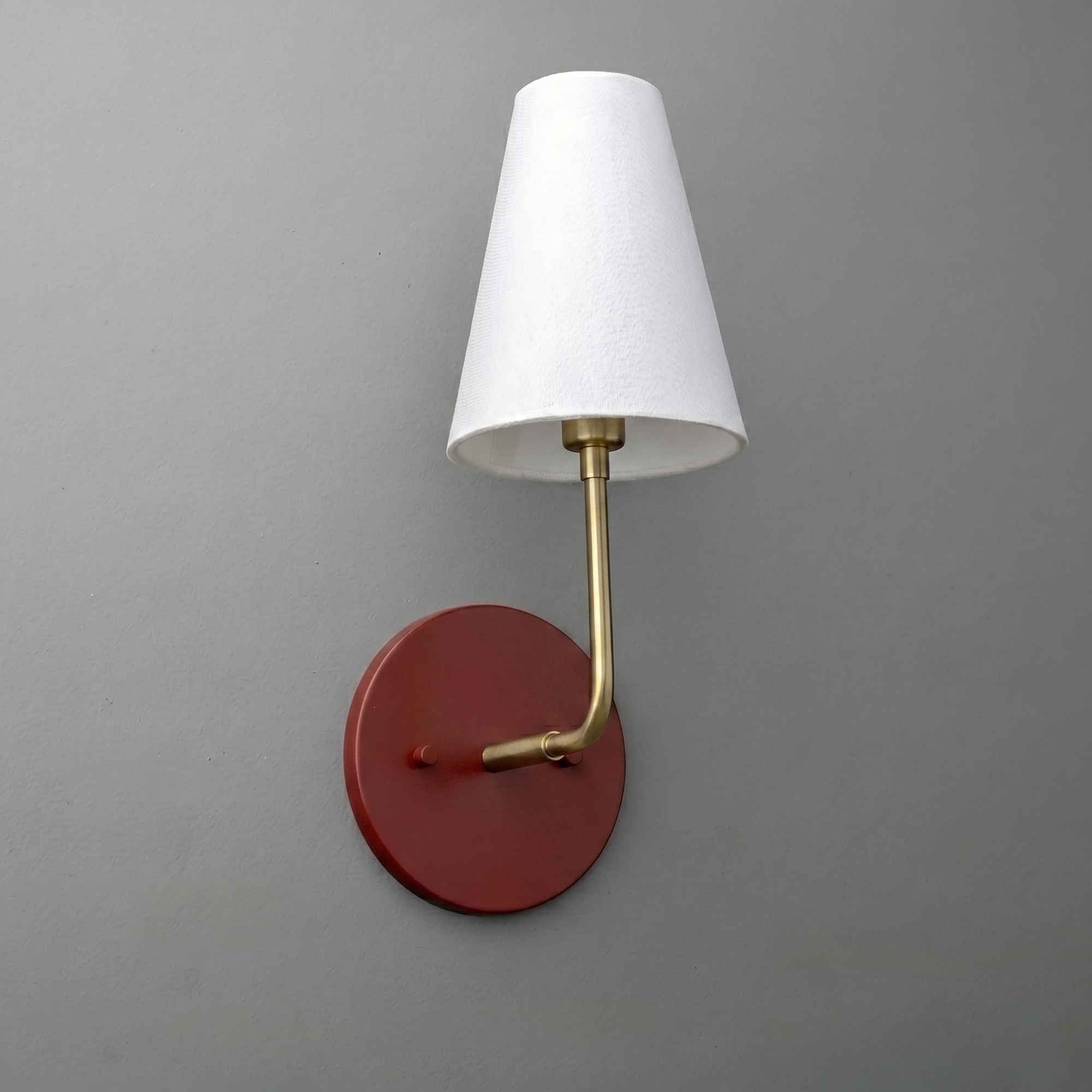 Wall sconce with round rust-colored metal base, brass arm, and white tapered fabric shade. - SCONCE MODEL NO. 3928