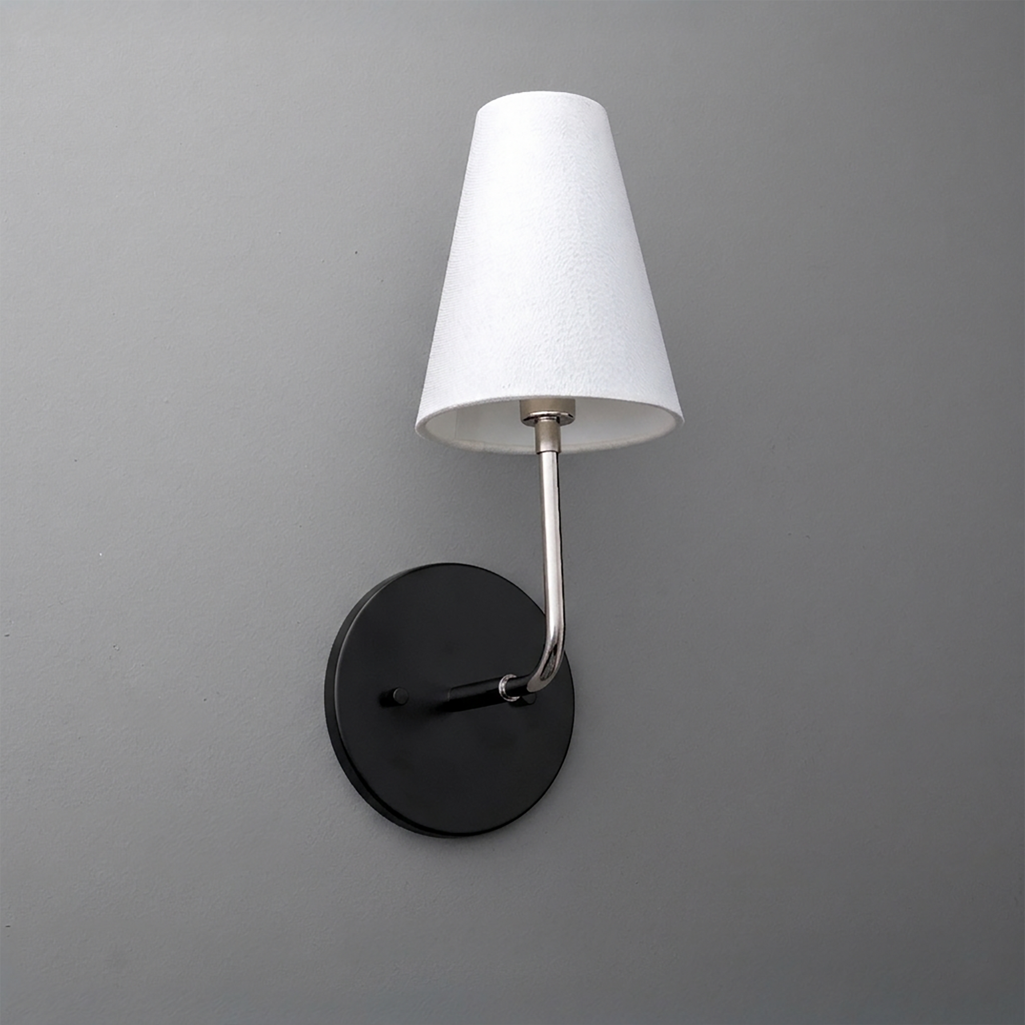 Wall-mounted sconce with black round base, brushed metal arm, and white tapered fabric shade. - SCONCE MODEL NO. 3928