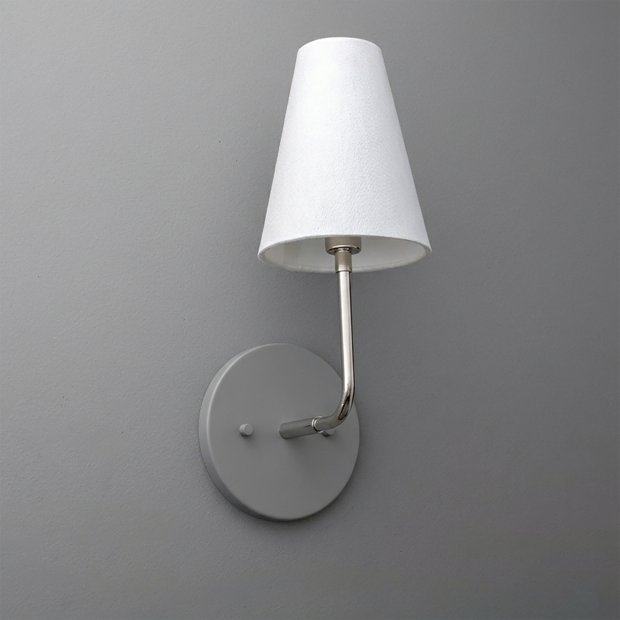 Metal wall sconce with round base and curved arm holding a white fabric tapered lampshade. - SCONCE MODEL NO. 3928