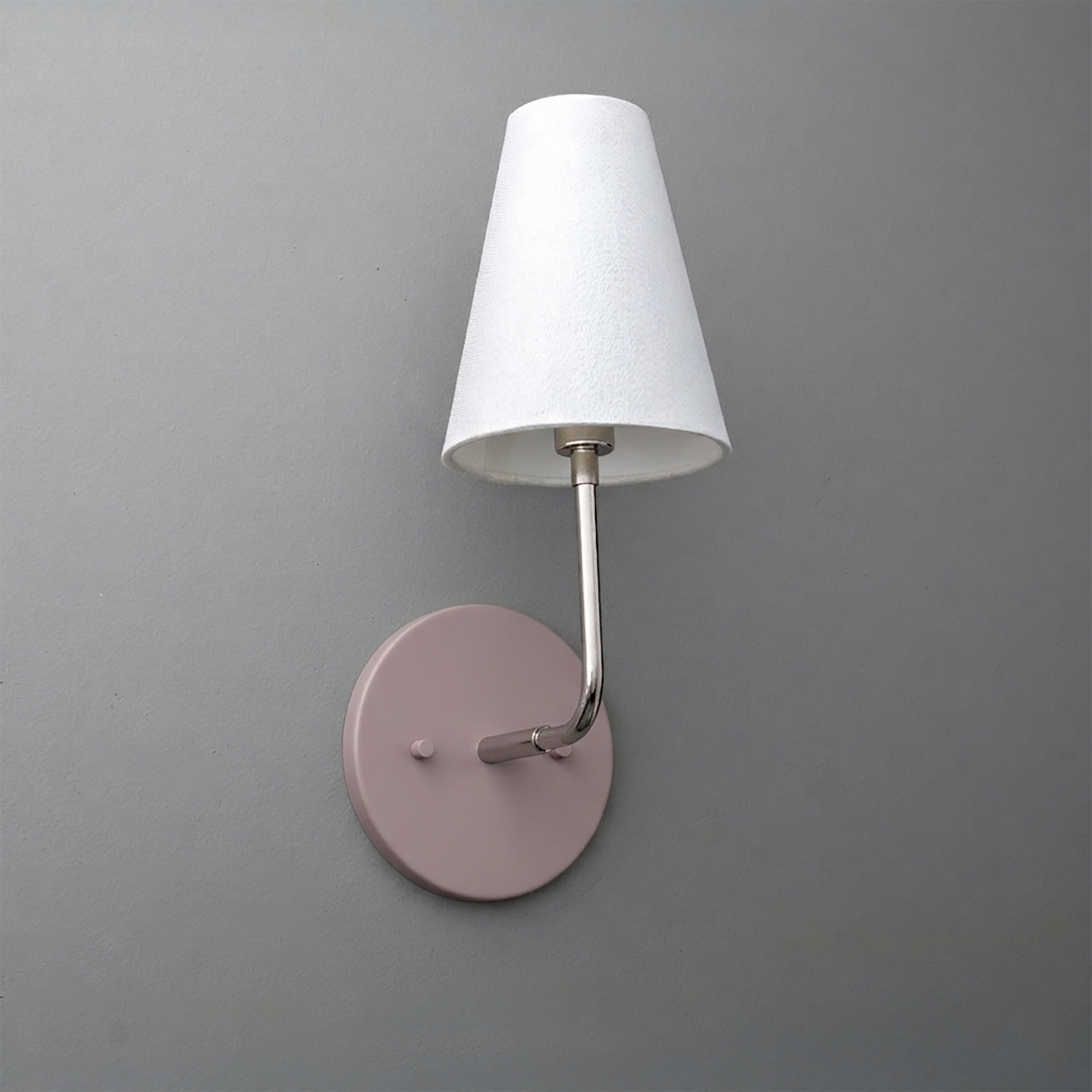 Wall-mounted single-bulb sconce with a round pink metal base and white tapered fabric shade. - SCONCE MODEL NO. 3928