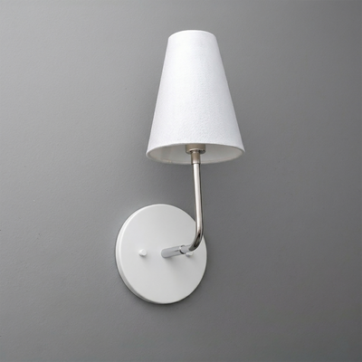 White metal wall sconce with round base and straight arm holding a tapered white fabric shade. - SCONCE MODEL NO. 3928