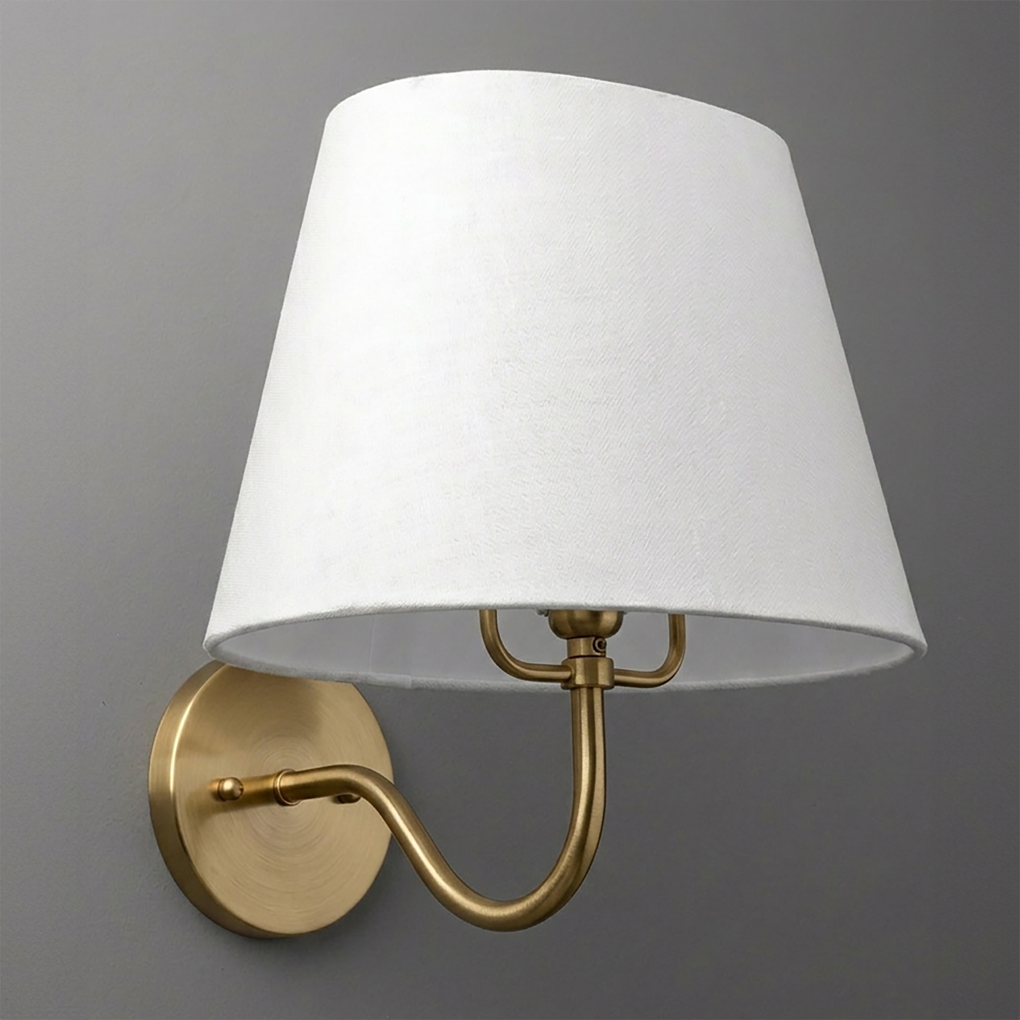 Brushed brass wall sconce with curved arm and white tapered fabric lampshade. - SCONCE MODEL NO. 0303