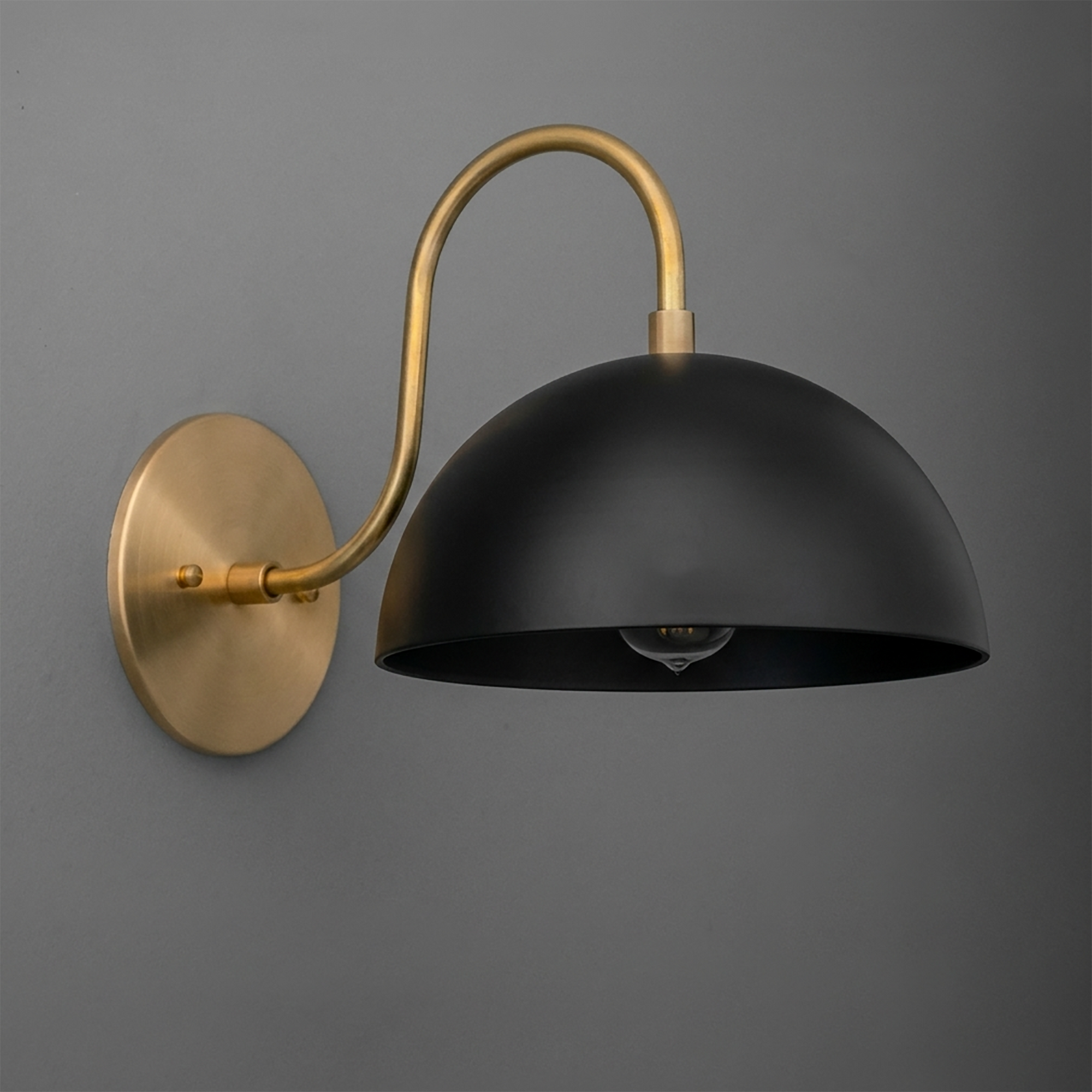 Black matte dome-shaped metal shade sconce with curved brushed brass arm and round wall mount. - SCONCE MODEL NO. 9092