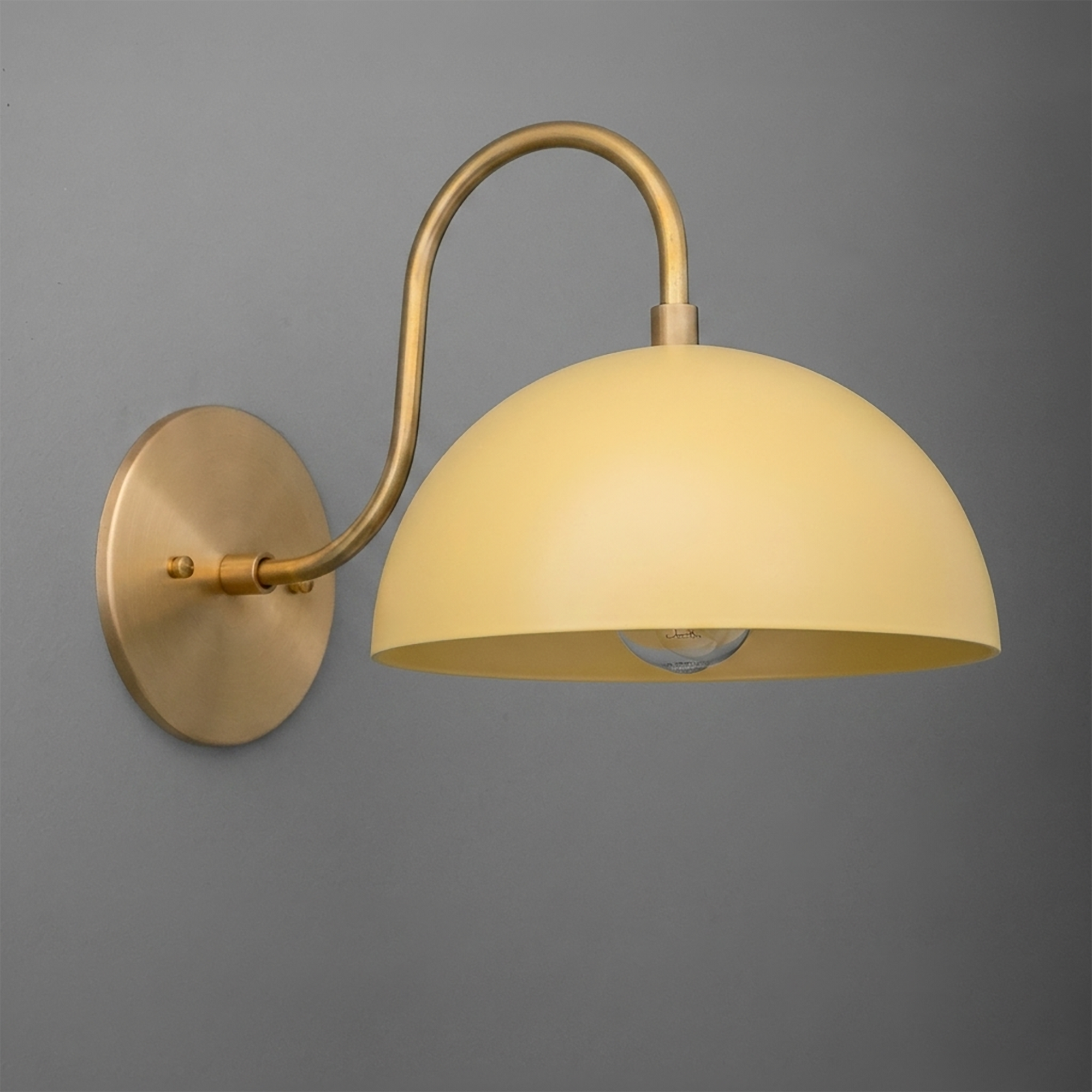 Matte brass wall sconce with a curved arm and a smooth yellow dome-shaped shade. - SCONCE MODEL NO. 9092