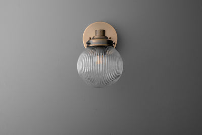 Wall sconce with ribbed clear glass globe and antique brass finish mounting plate. - SCONCE MODEL NO. 7273