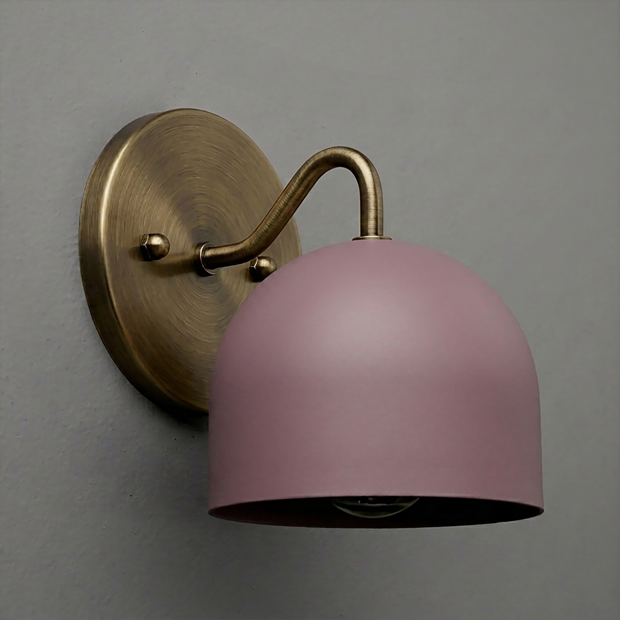 Wall-mounted sconce with a brass base and curved arm, featuring a smooth matte pink dome-shaped shade. - SCONCE MODEL NO. 9436
