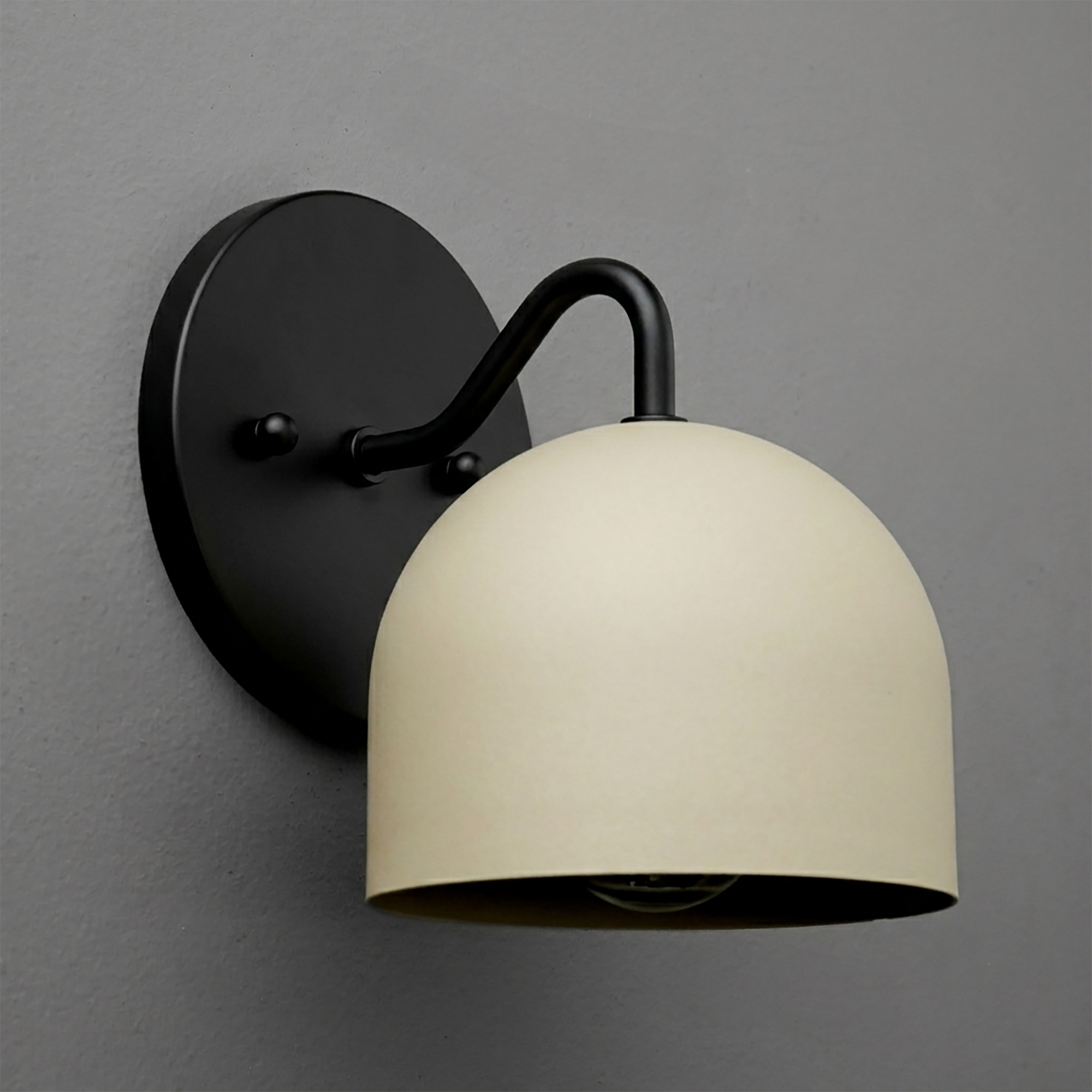 Matte black metal wall sconce with curved arm and cream dome-shaped shade covering bulb. - SCONCE MODEL NO. 9436
