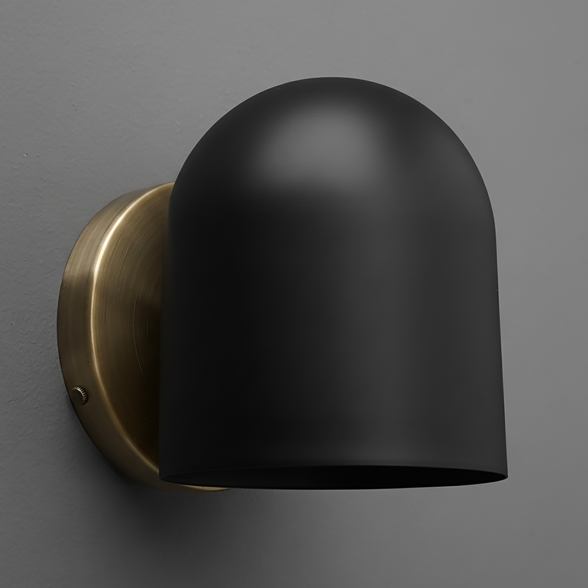 Matte black dome-shaped metal sconce with antique brass round wall mount against gray background. - SCONCE MODEL NO. 2424