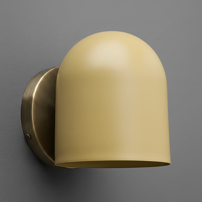Matte beige dome-shaped sconce with smooth metal base in antique brass finish mounted on gray wall. - SCONCE MODEL NO. 2424