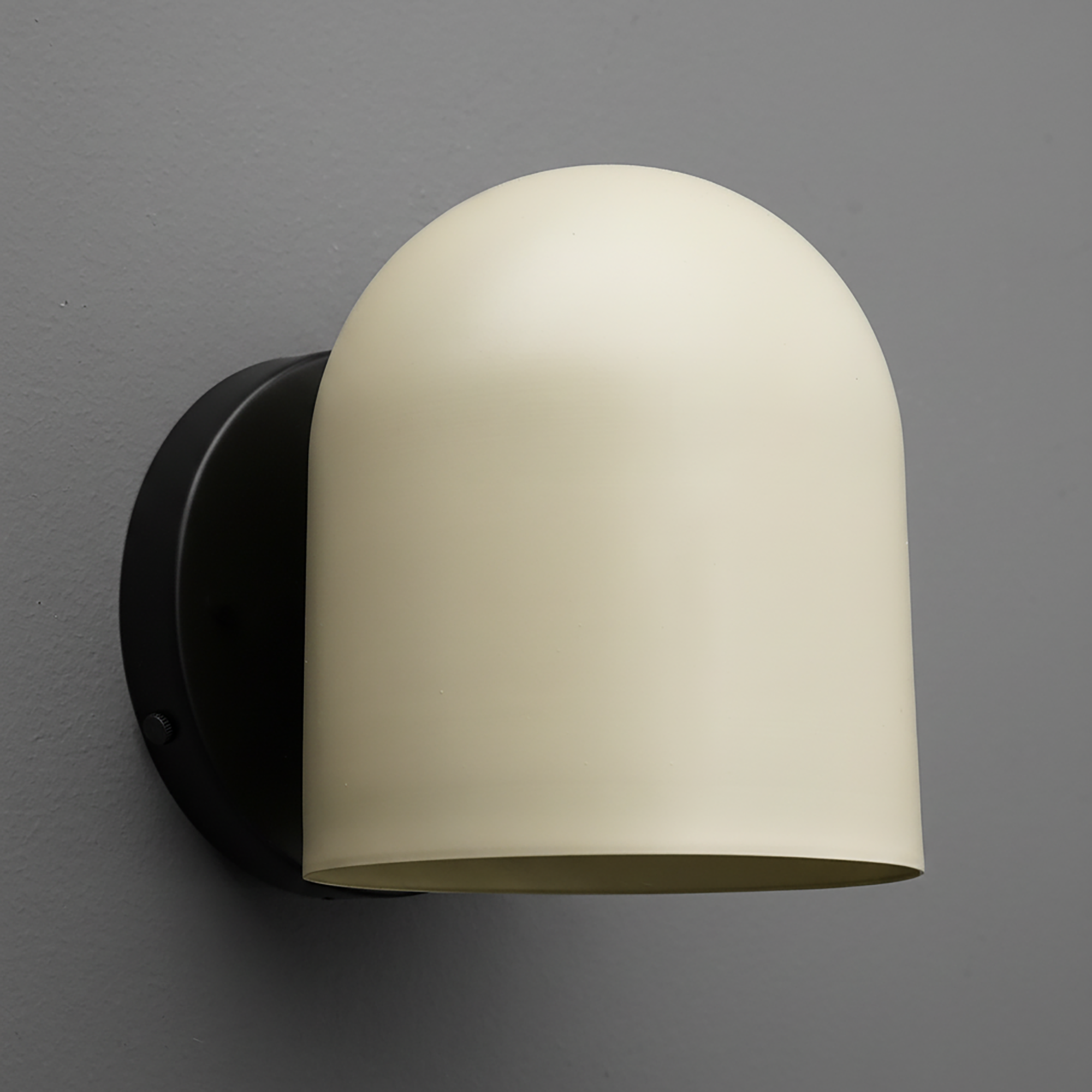 Matte black metal wall sconce with a smooth, rounded ivory cream shade covering the light source. - SCONCE MODEL NO. 2424