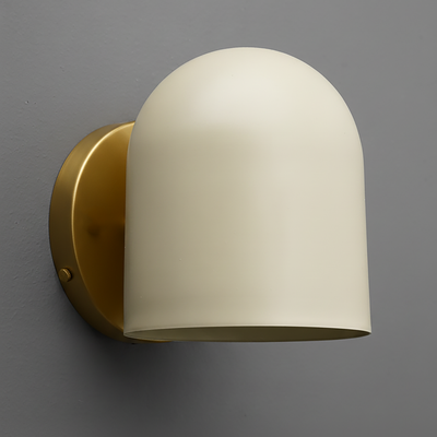 Cream-colored metal sconce with smooth dome shade and antique brass round backplate mounted on gray wall. - SCONCE MODEL NO. 2424