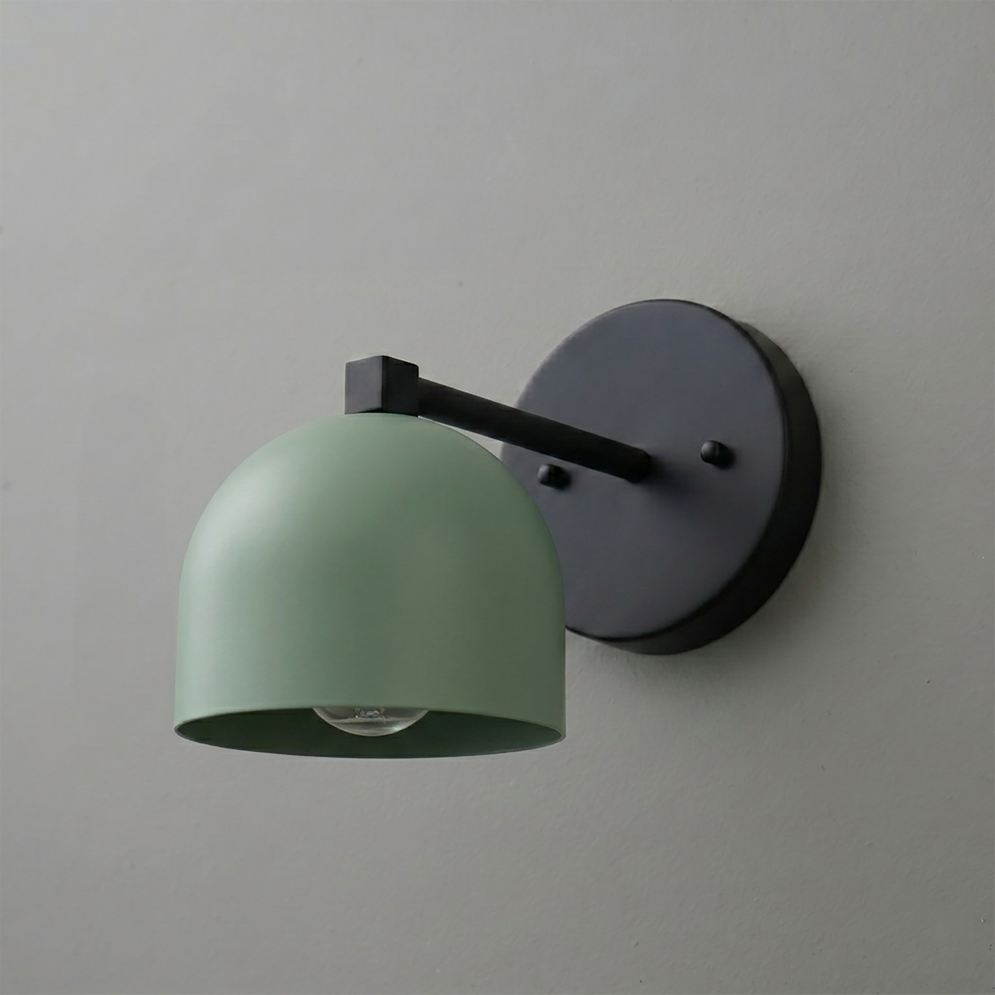 Matte black wall sconce with a curved arm and matte sage green dome-shaped metal shade covering one bulb. - SCONCE MODEL NO. 3622