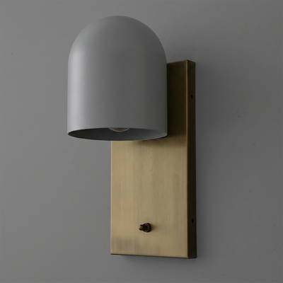 Matte gray dome-shaped metal sconce with single bulb mounted on a rectangular brushed brass backplate with a small black. - SCONCE MODEL NO. 6029