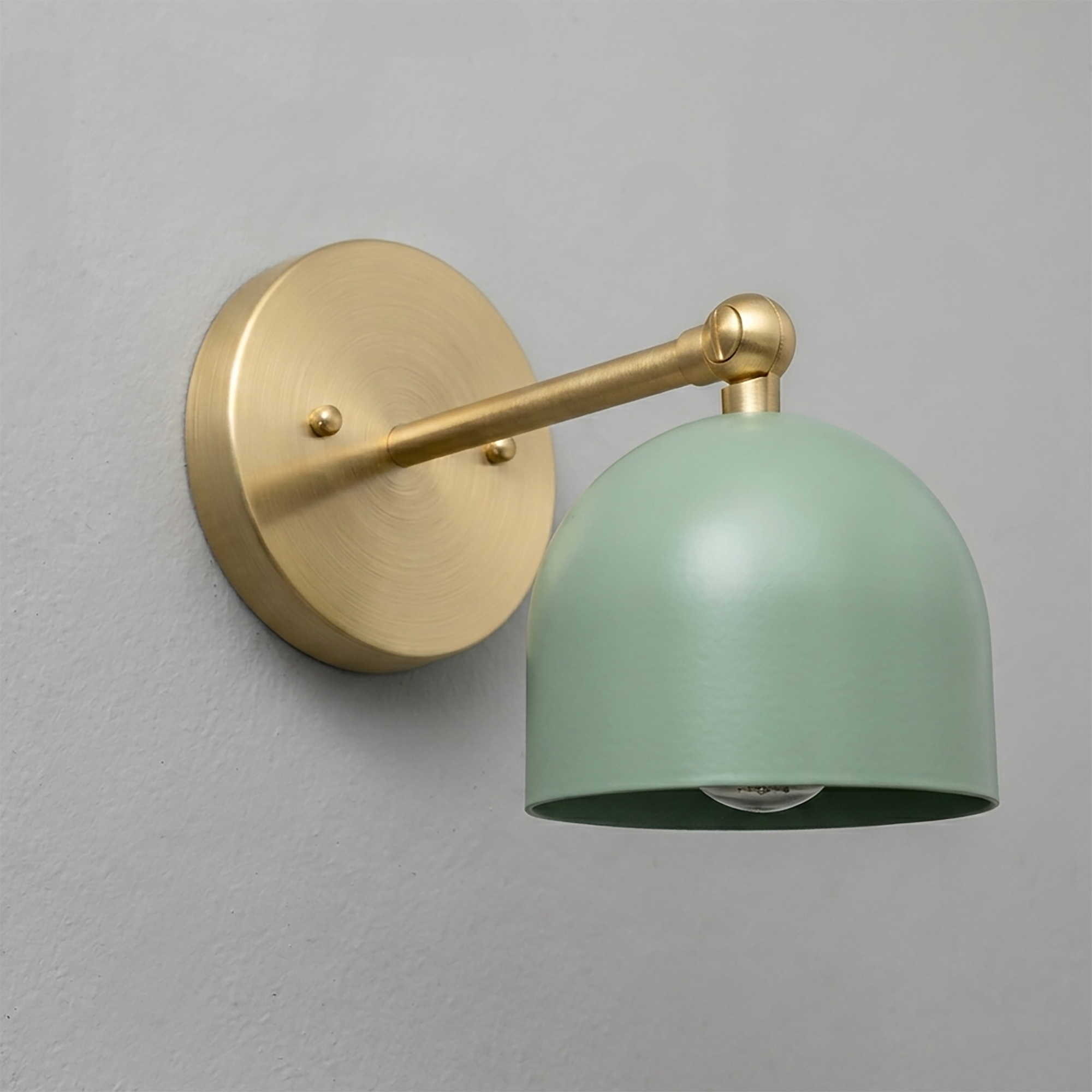 Wall sconce with matte brass round backplate and arm, featuring a smooth sage green dome-shaped metal shade. - SCONCE MODEL NO. 5103