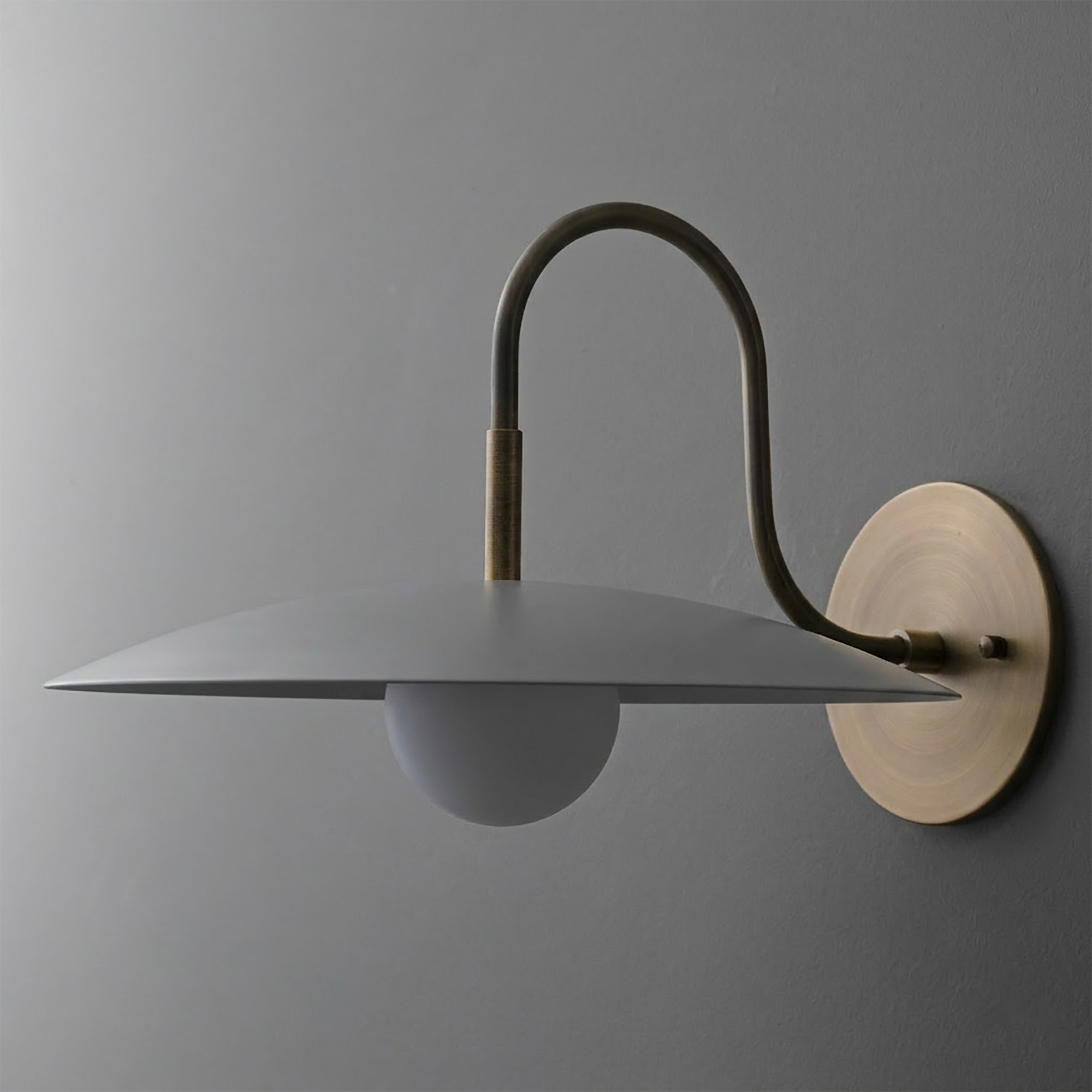 Wall sconce with matte gray wide dome shade, white globe bulb, and brushed brass curved arm and round mount. - SCONCE MODEL NO. 9171