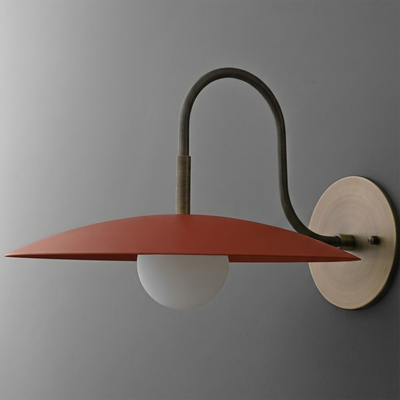 Wall sconce with a matte red flat disc shade, frosted globe bulb, and curved dark metal arm on a round beige mount. - SCONCE MODEL NO. 9171