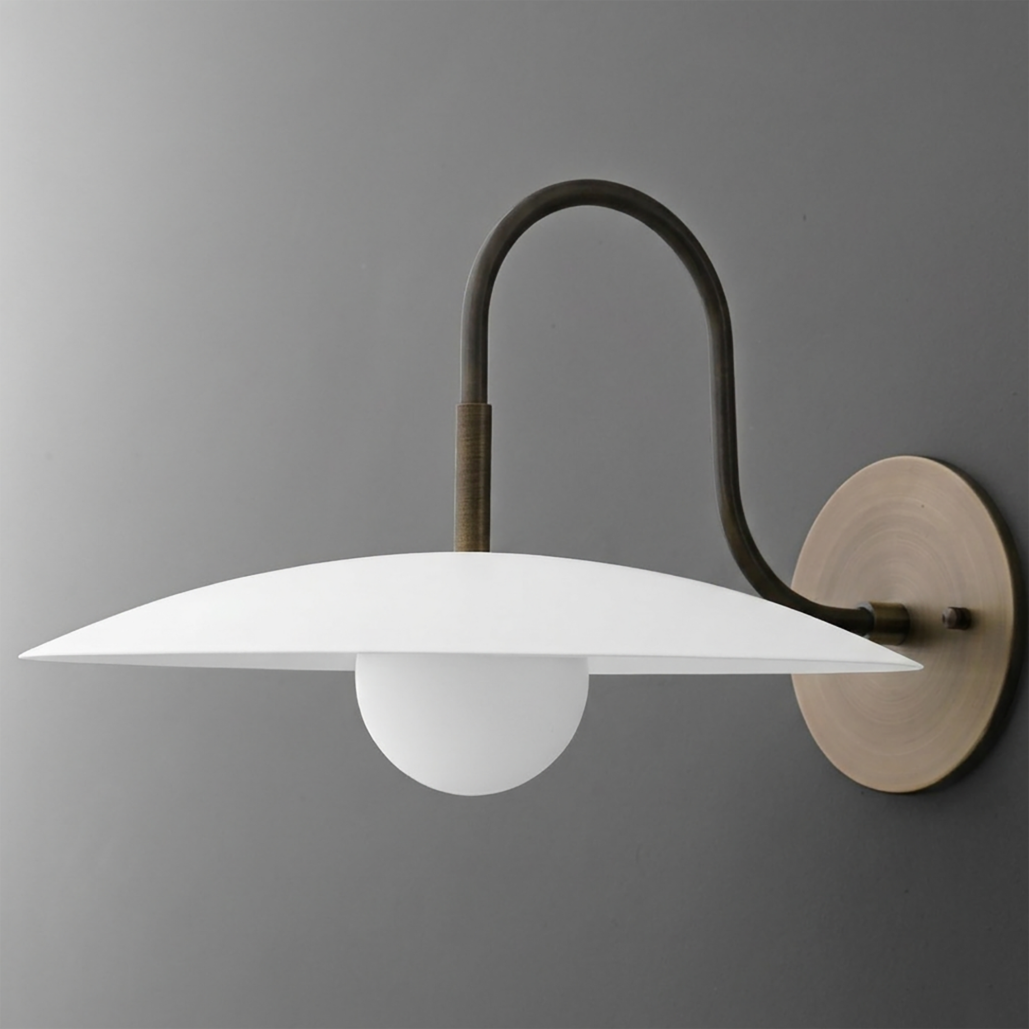 Wall-mounted sconce with curved dark metal arm, round beige base, and flat white disc shade over frosted globe bulb. - SCONCE MODEL NO. 9171