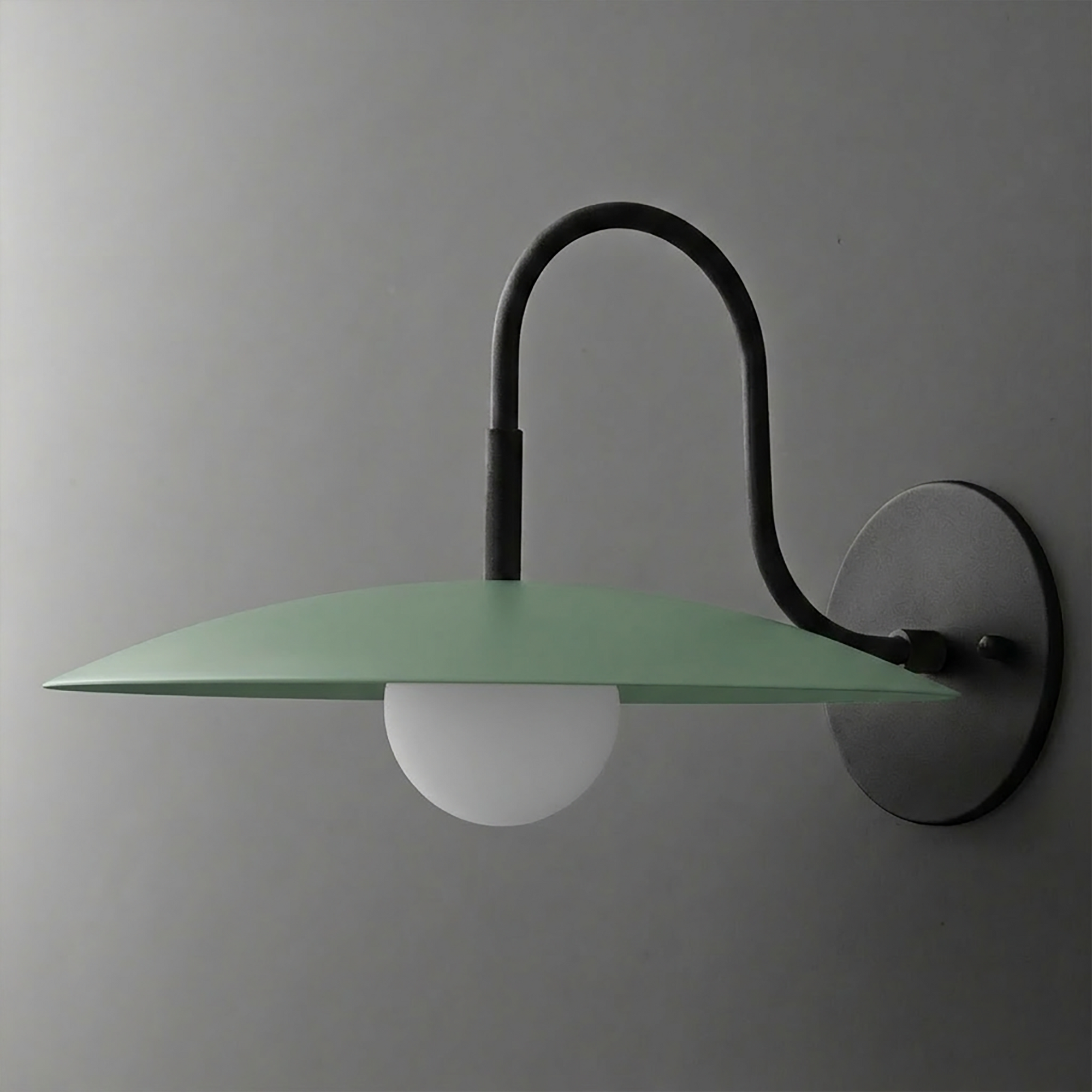 Matte black metal wall sconce with curved arm and wide, flat green metal shade over a white globe bulb. - SCONCE MODEL NO. 9171
