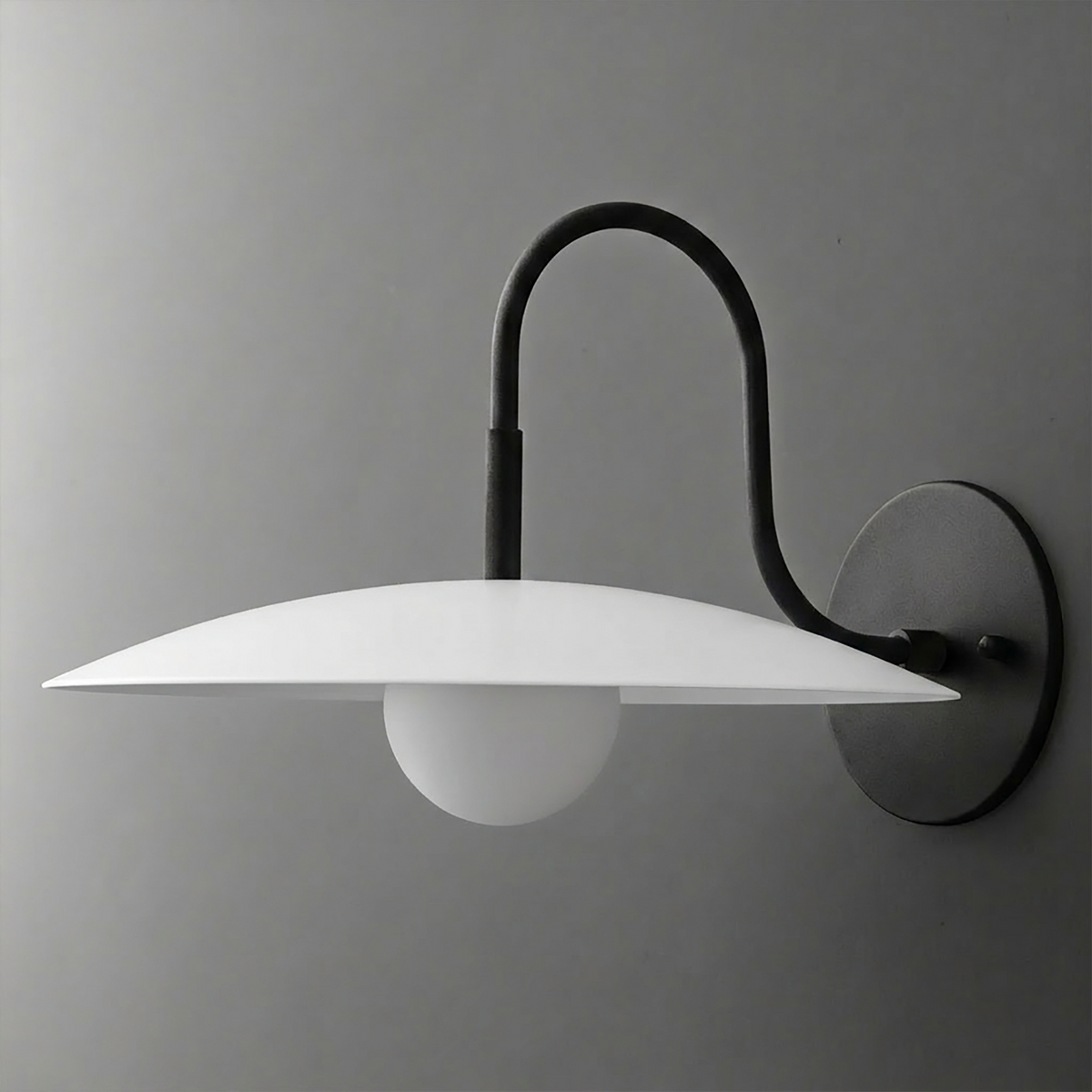 Black metal wall sconce with curved arm, flat white disc shade, and round frosted bulb. - SCONCE MODEL NO. 9171