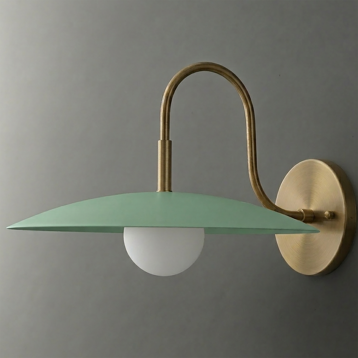Wall sconce with a matte green flat disc shade, matte white globe bulb, and brushed brass curved arm and round wall mount. - SCONCE MODEL NO. 9171