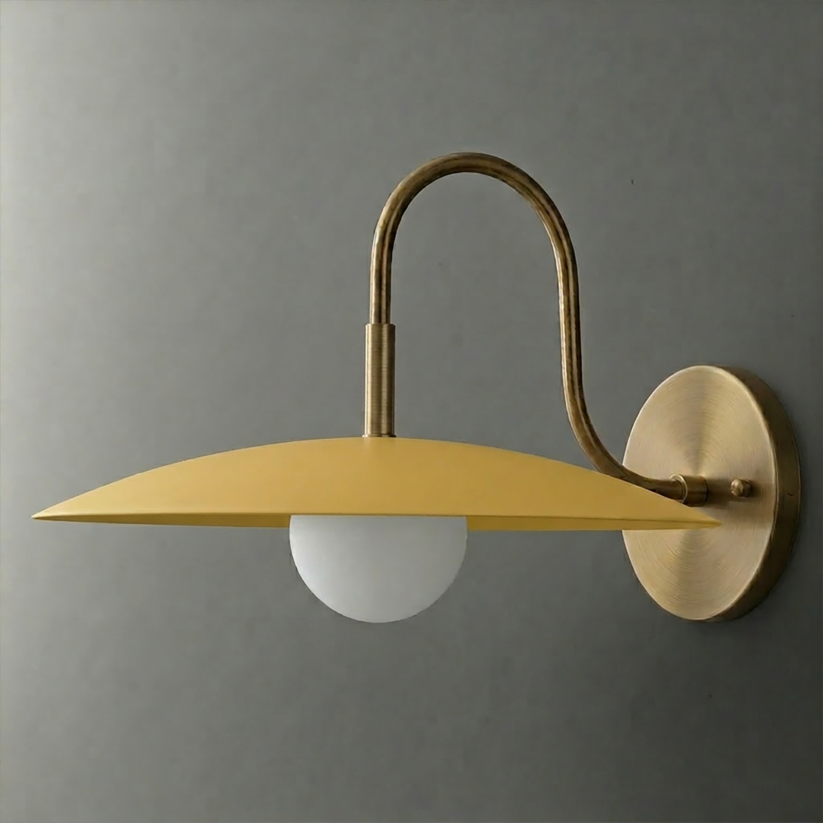 Mustard yellow metal shade sconce with frosted globe bulb and brushed brass curved arm and round wall mount. - SCONCE MODEL NO. 9171