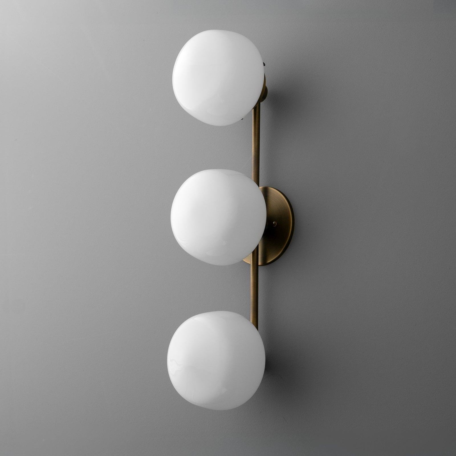 Three-bulb vanity light with matte white glass globes and brushed brass vertical fixture. - VANITY LIGHT MODEL NO. 1106