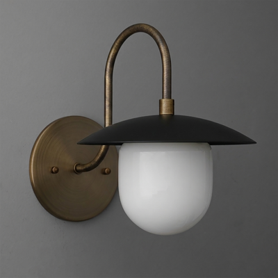 Wall-mounted sconce with aged brass round base, curved arm, matte black flat dome shade, and frosted white glass globe light - SCONCE MODEL NO. 7191