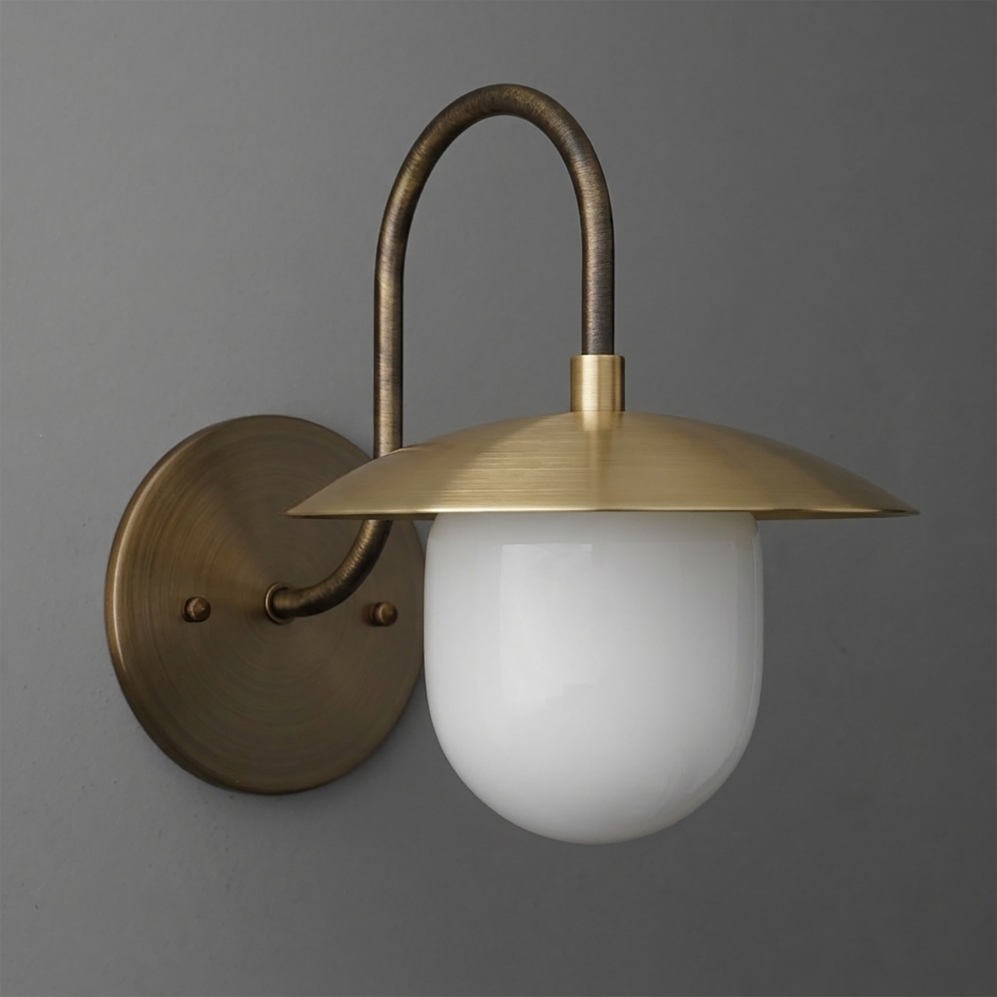 Antique brass wall sconce with curved arm and white frosted glass shade with flat, wide brass top. - SCONCE MODEL NO. 7191