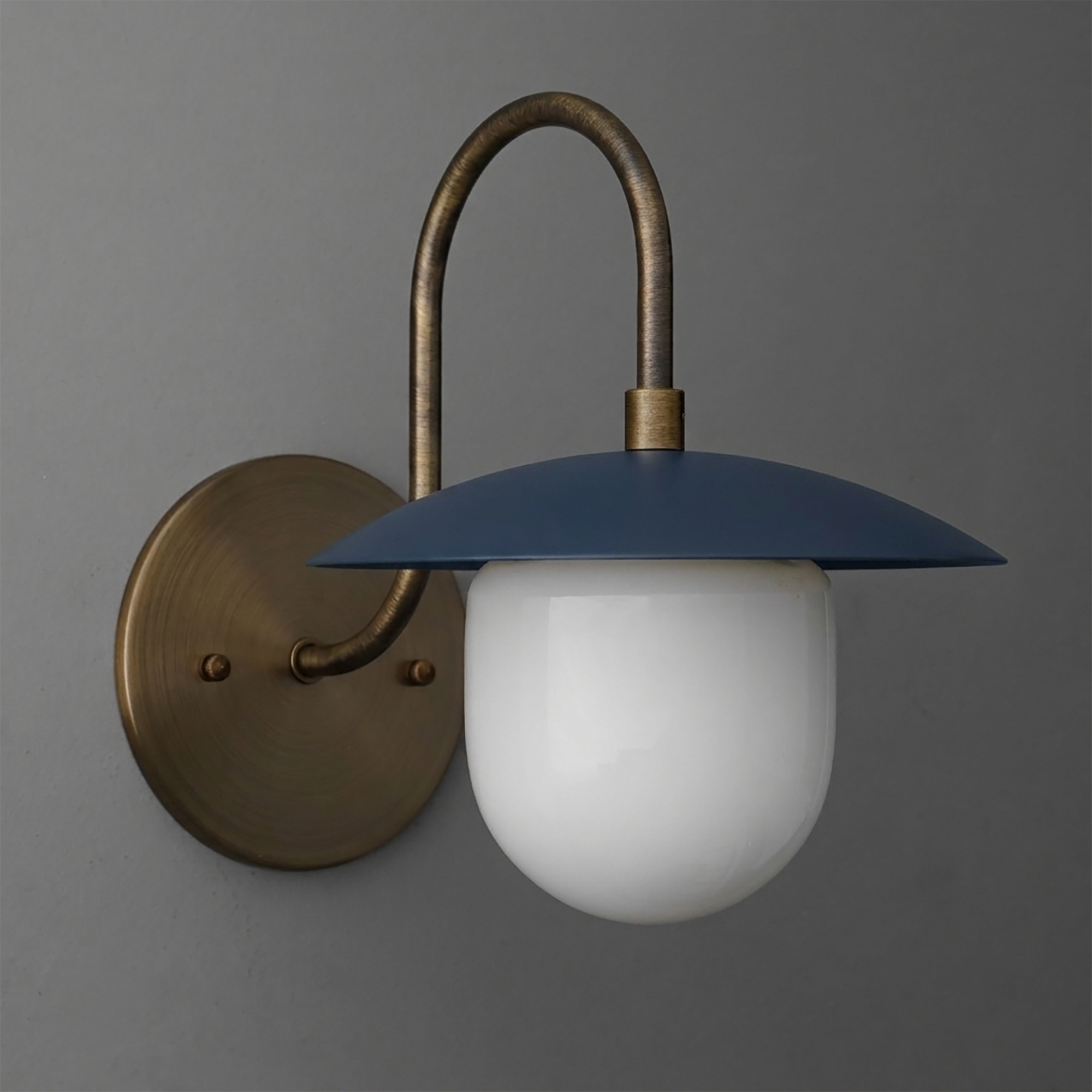Wall sconce with curved antique brass arm, round backplate, and flat blue metal shade over white glass globe diffuser. - SCONCE MODEL NO. 7191