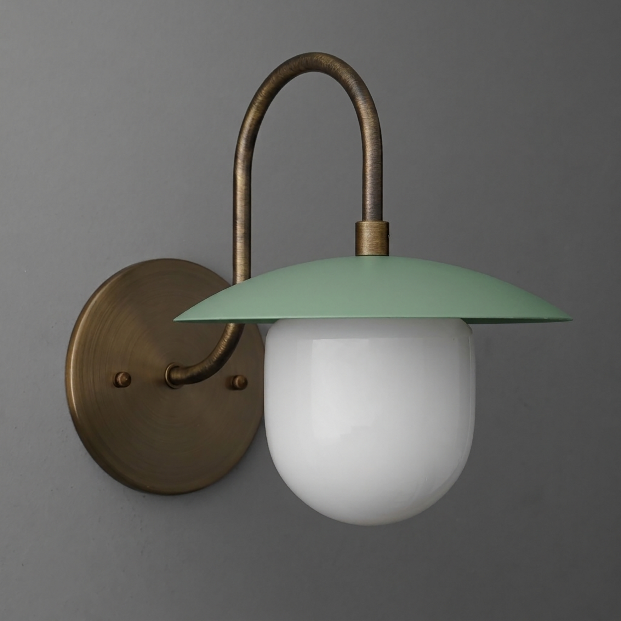 Wall sconce with antique brass curved arm and round backplate, matte green metal shade, and white frosted glass globe bulb. - SCONCE MODEL NO. 7191