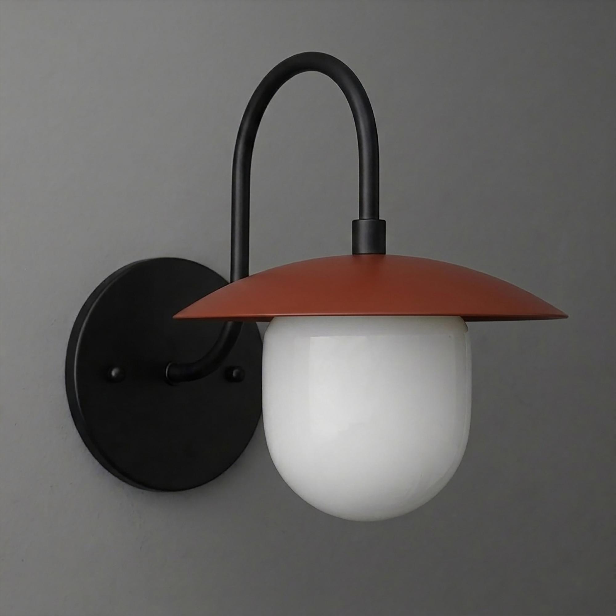 Wall-mounted sconce with matte black metal arm and round backplate, featuring a rust-colored conical shade and frosted white - SCONCE MODEL NO. 7191