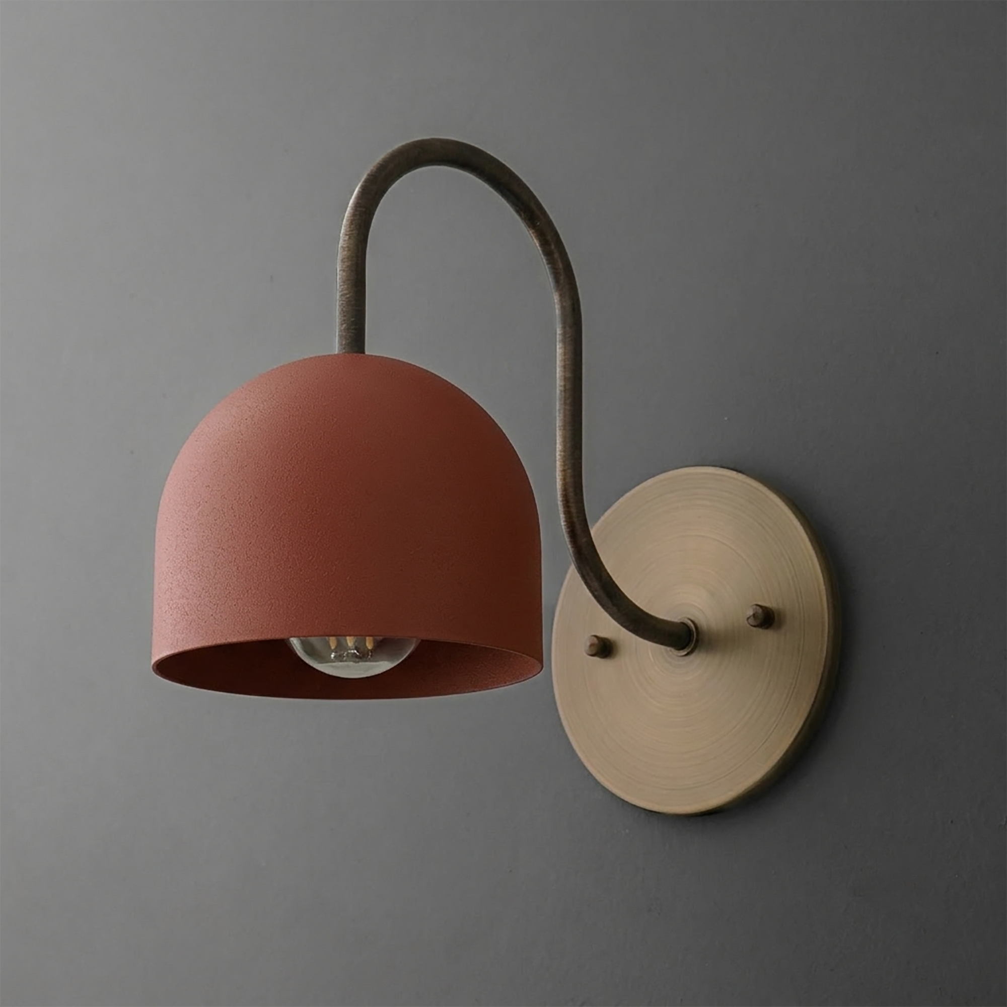 Wall sconce with matte terracotta dome shade, curved dark metal arm, and round brass mounting plate. - SCONCE MODEL NO. 6308