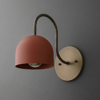 Wall sconce with matte terracotta dome shade, curved dark metal arm, and round brass mounting plate. - SCONCE MODEL NO. 6308