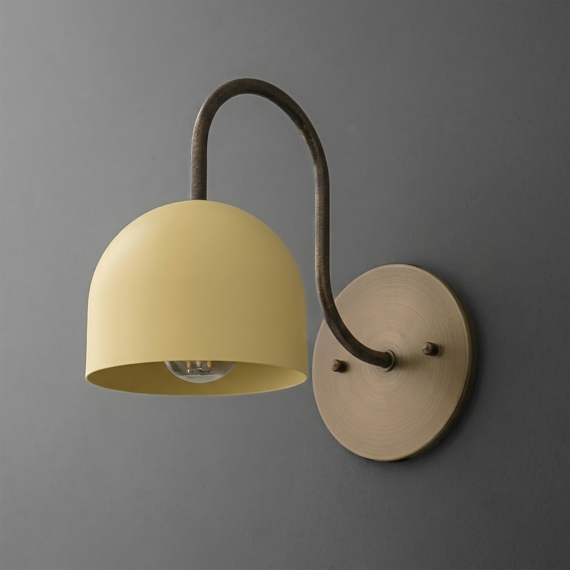 Wall-mounted sconce with matte yellow dome shade and curved dark metal arm attaching to round brass backplate. - SCONCE MODEL NO. 6308
