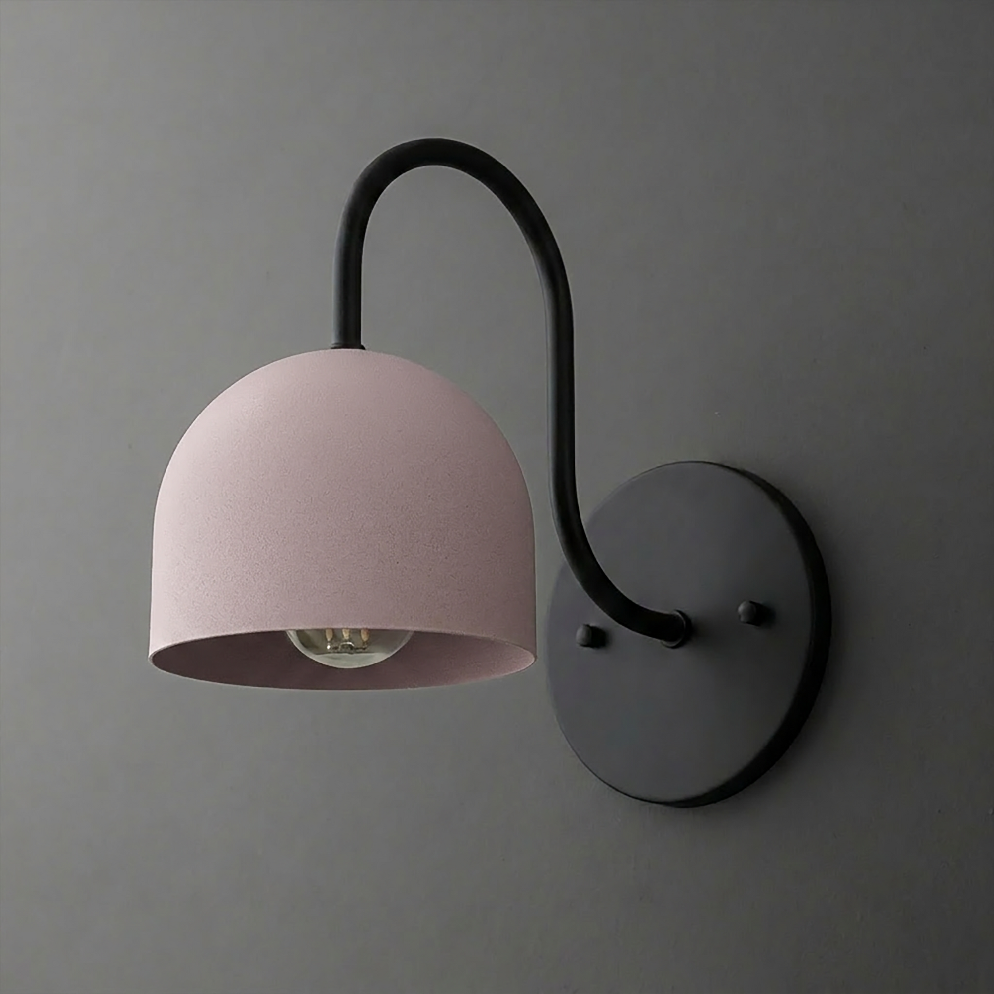 Black metal wall sconce with curved arm and dome-shaped matte pink lampshade, single bulb exposed below shade. - SCONCE MODEL NO. 6308
