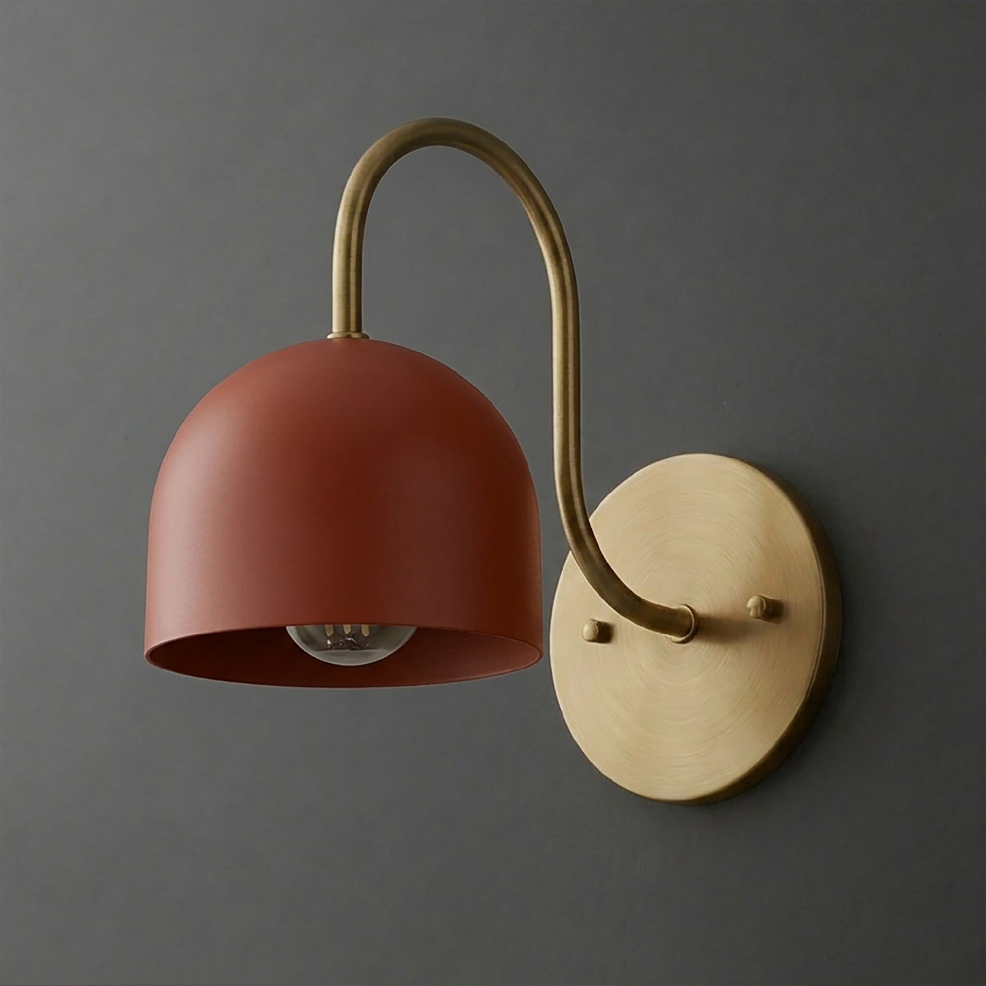 Wall sconce with matte rust red dome shade and curved brass arm mounted on round brass base. - SCONCE MODEL NO. 6308