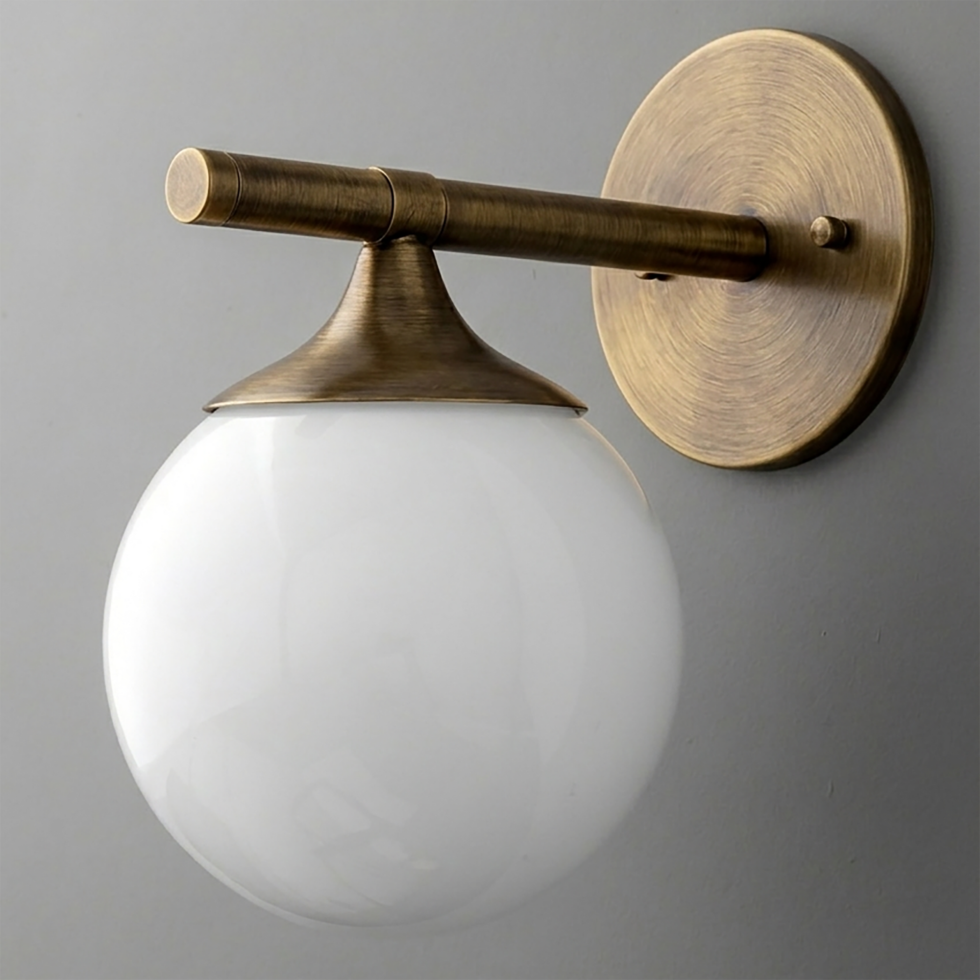 Antique brass wall sconce with a round backplate and white glass globe shade. - SCONCE MODEL NO. 1098