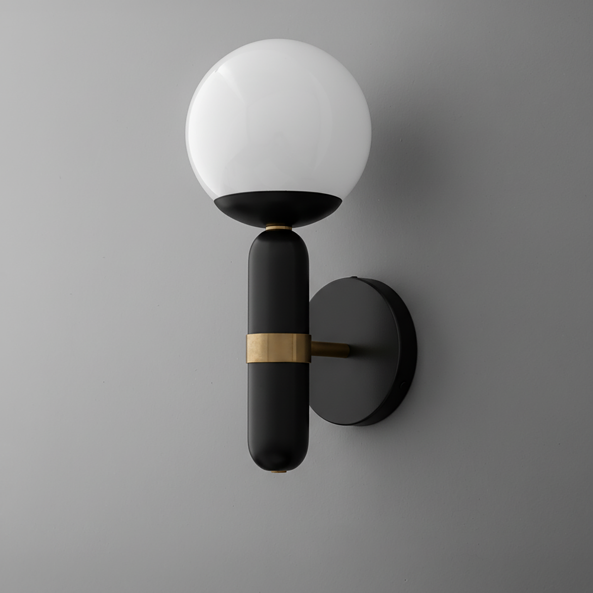 Wall sconce with round white glass shade and black cylindrical base featuring a brass accent band. - SCONCE MODEL NO. 4786