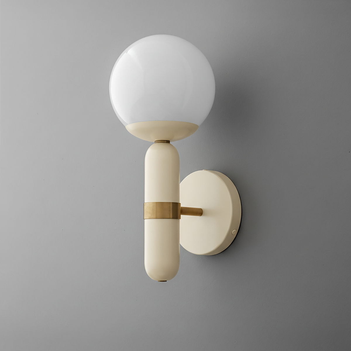Wall sconce with matte cream cylindrical base, brass accent, and round white glass globe shade. - SCONCE MODEL NO. 4786