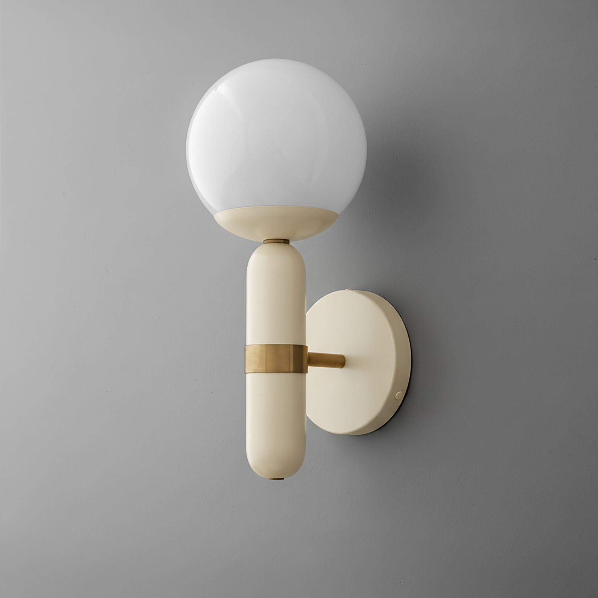 Wall sconce with matte cream cylindrical base, brass accent, and round white glass globe shade. - SCONCE MODEL NO. 4786