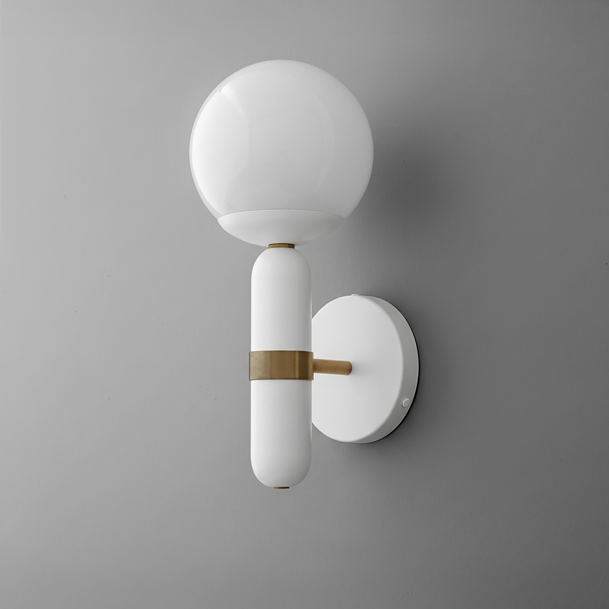 Wall sconce with round white glass globe and white cylindrical base with brass accent on gray wall. - SCONCE MODEL NO. 4786