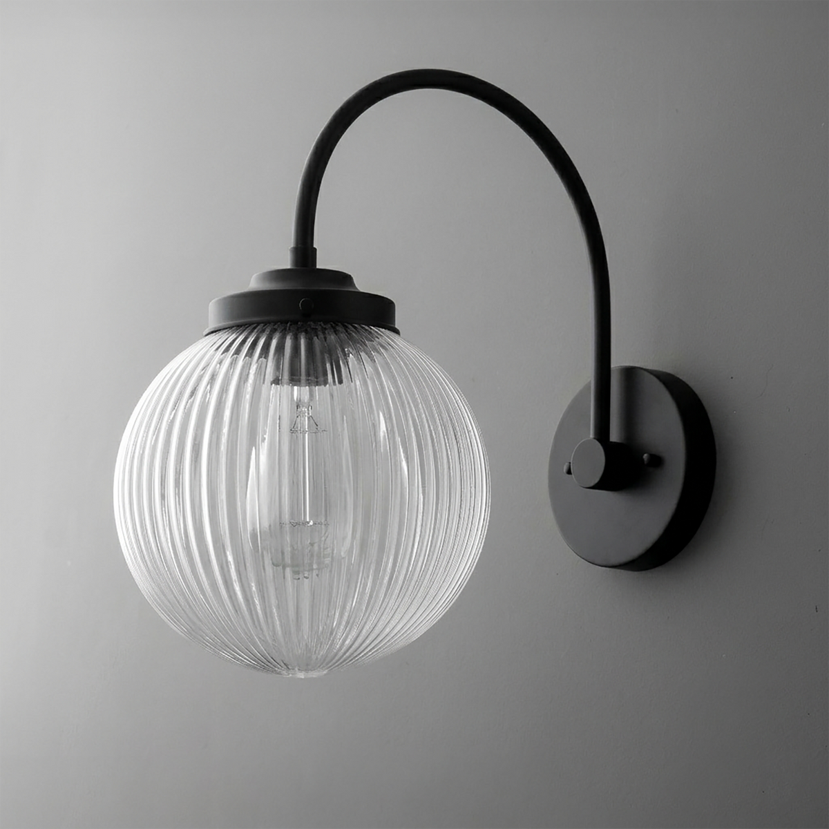 Black metal wall sconce with curved arm and ribbed clear glass globe shade. - SCONCE MODEL NO. 8763