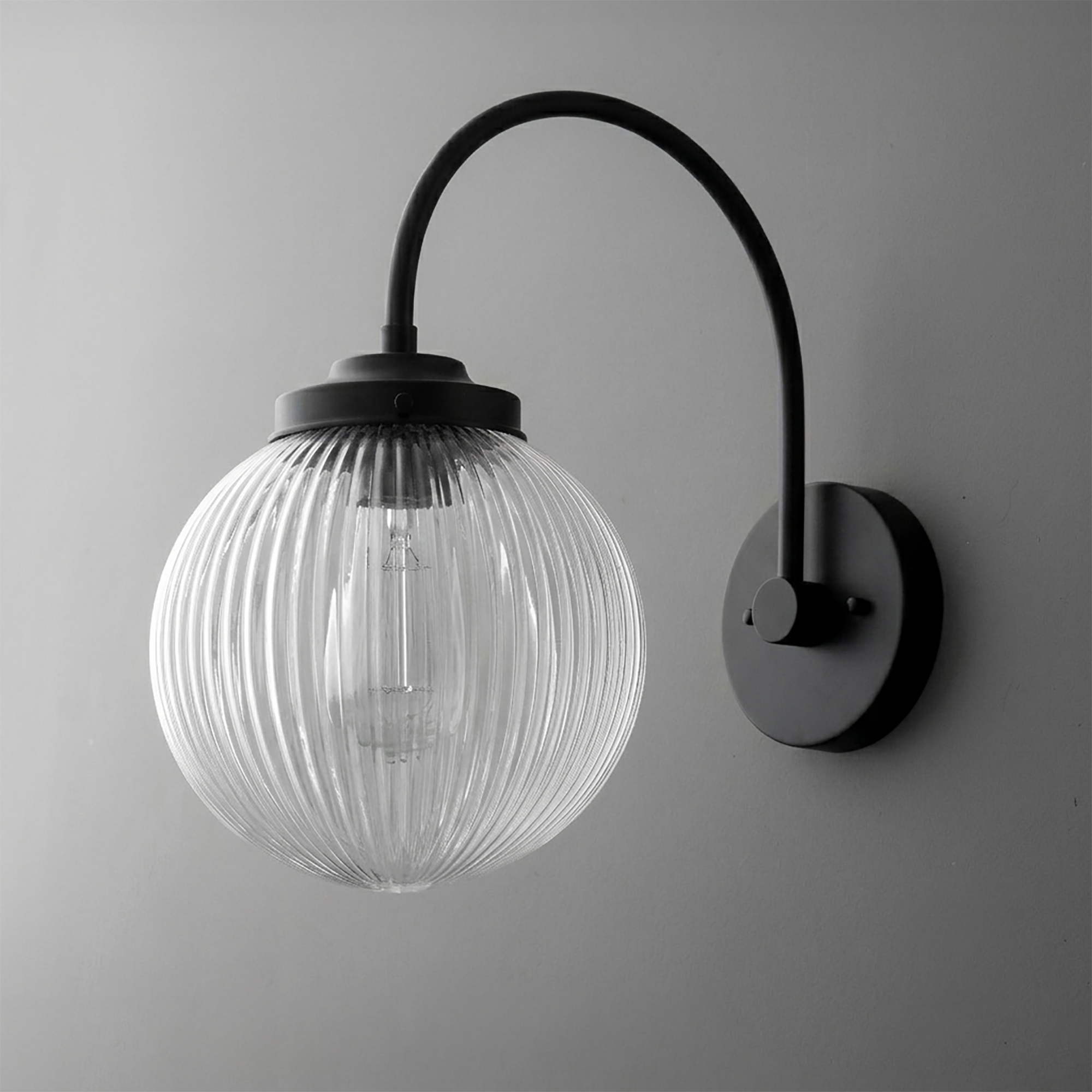 Black metal wall sconce with curved arm and ribbed clear glass globe shade. - SCONCE MODEL NO. 8763