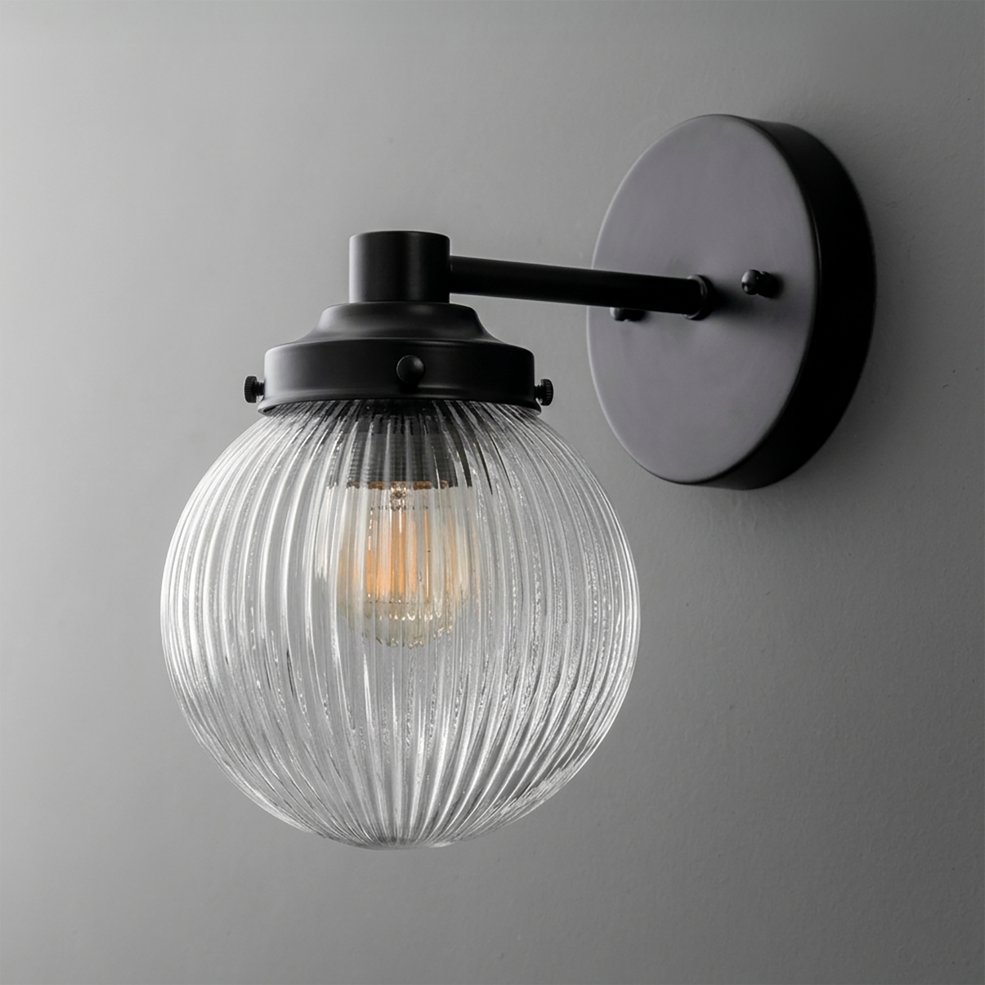 Wall-mounted black metal sconce with ribbed clear glass globe shade and visible bulb inside. - SCONCE MODEL NO. 7273
