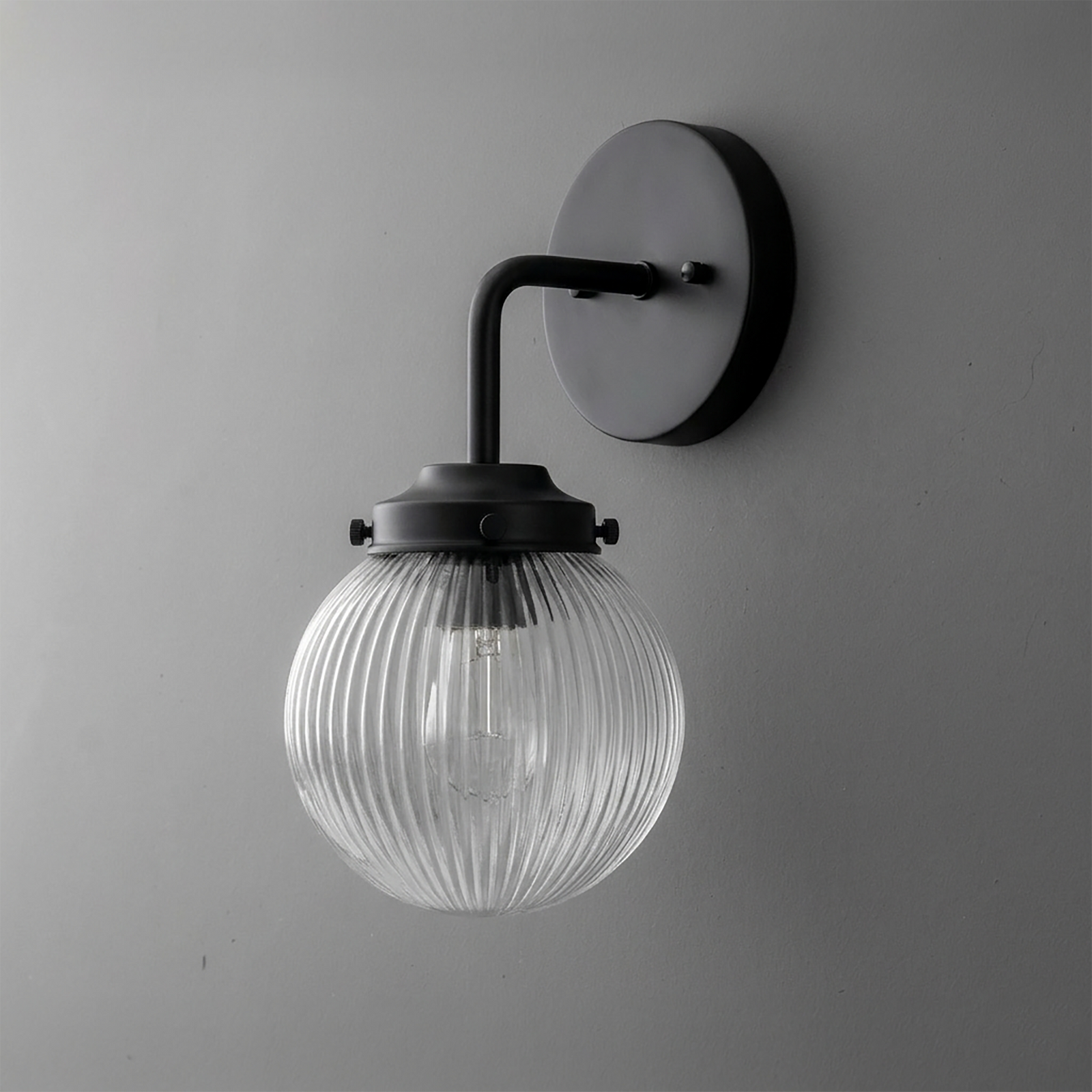Black metal wall sconce with ribbed clear glass globe shade and single bulb design. - SCONCE MODEL NO. 6857